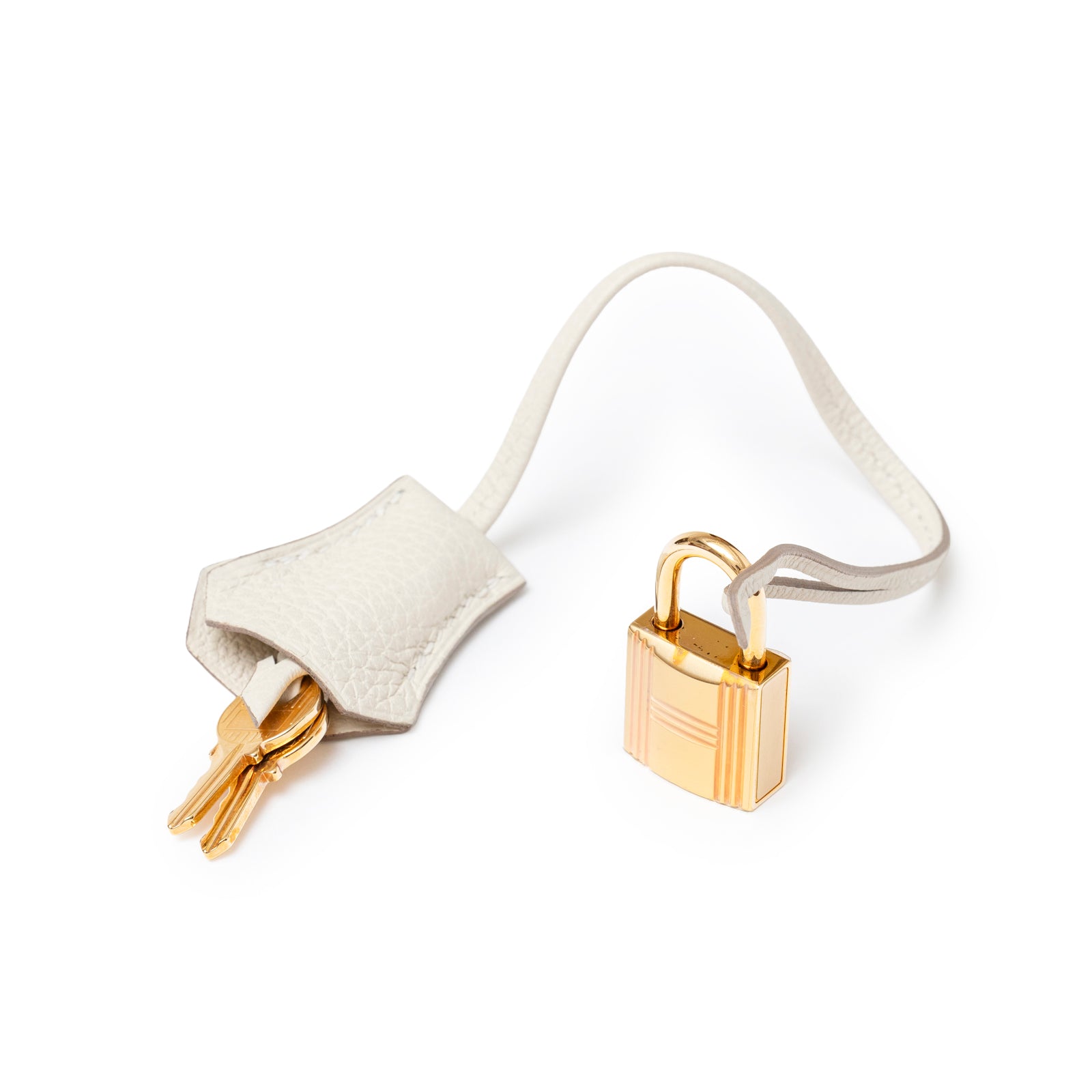 Close-up of Hermès Birkin 30 Craie Togo Rose Gold Hardware lock and key with leather clochette on white background