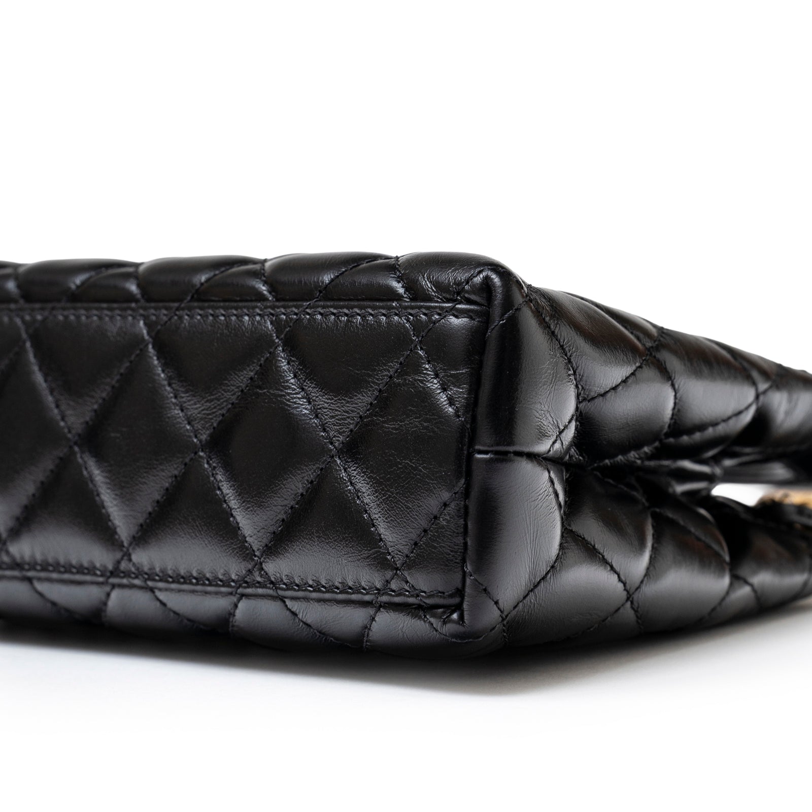 Close-up of quilted black leather base on Chanel Mini Kelly Shopper Black Shiny Aged Calfskin Brushed Gold Hardware