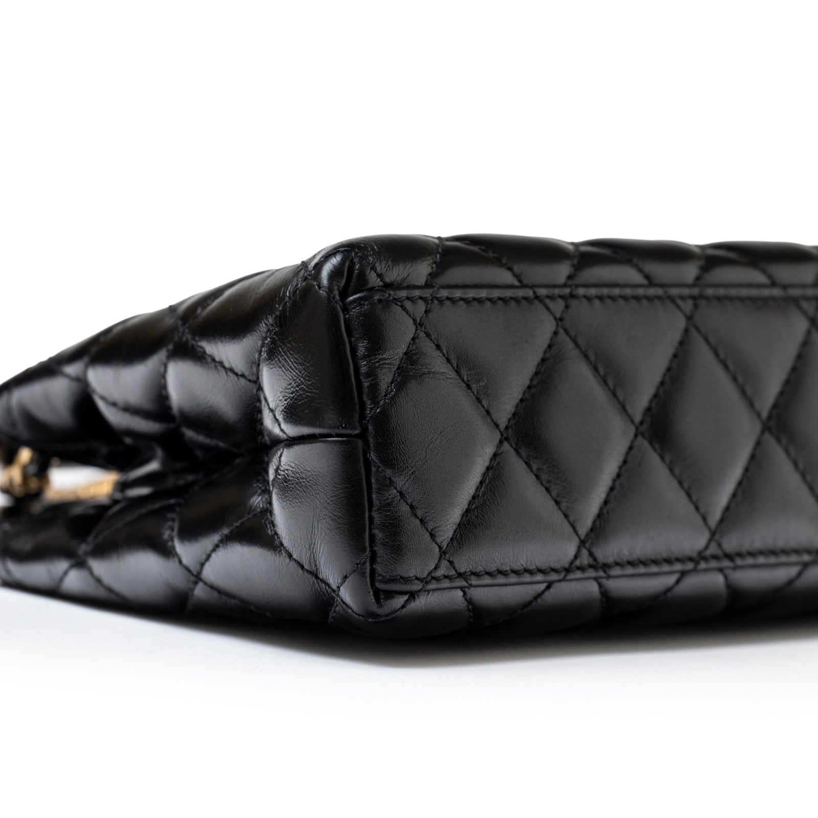 Close-up angled shot of the black shiny aged calfskin on Chanel Mini Kelly Shopper Black Shiny Aged Calfskin Brushed Gold Hardware