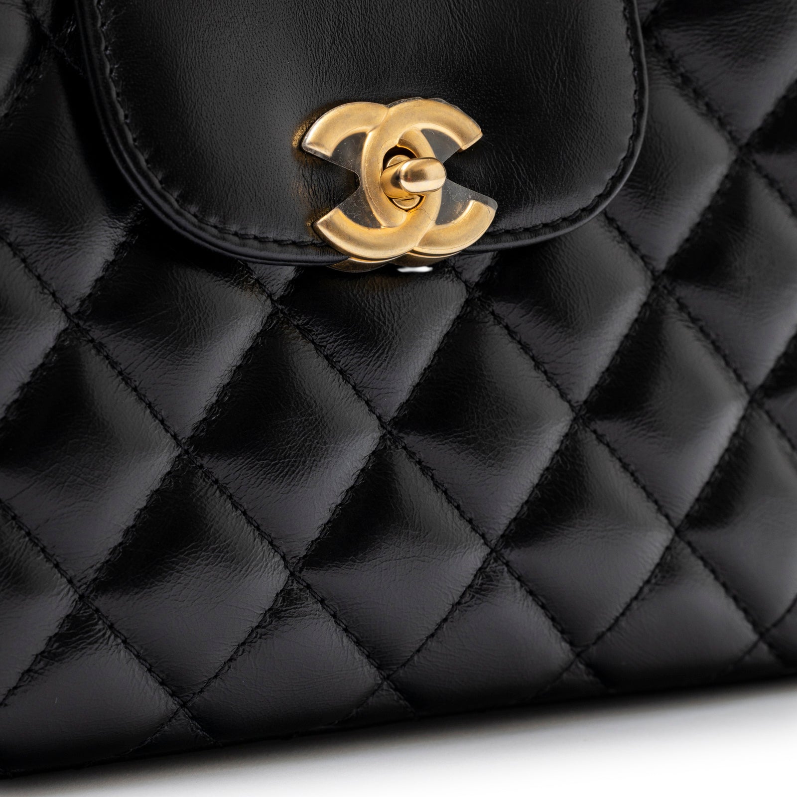 Close-up of brushed gold hardware and black shiny aged calfskin quilted leather on Chanel Mini Kelly Shopper Black Shiny Aged Calfskin Brushed Gold Hardware