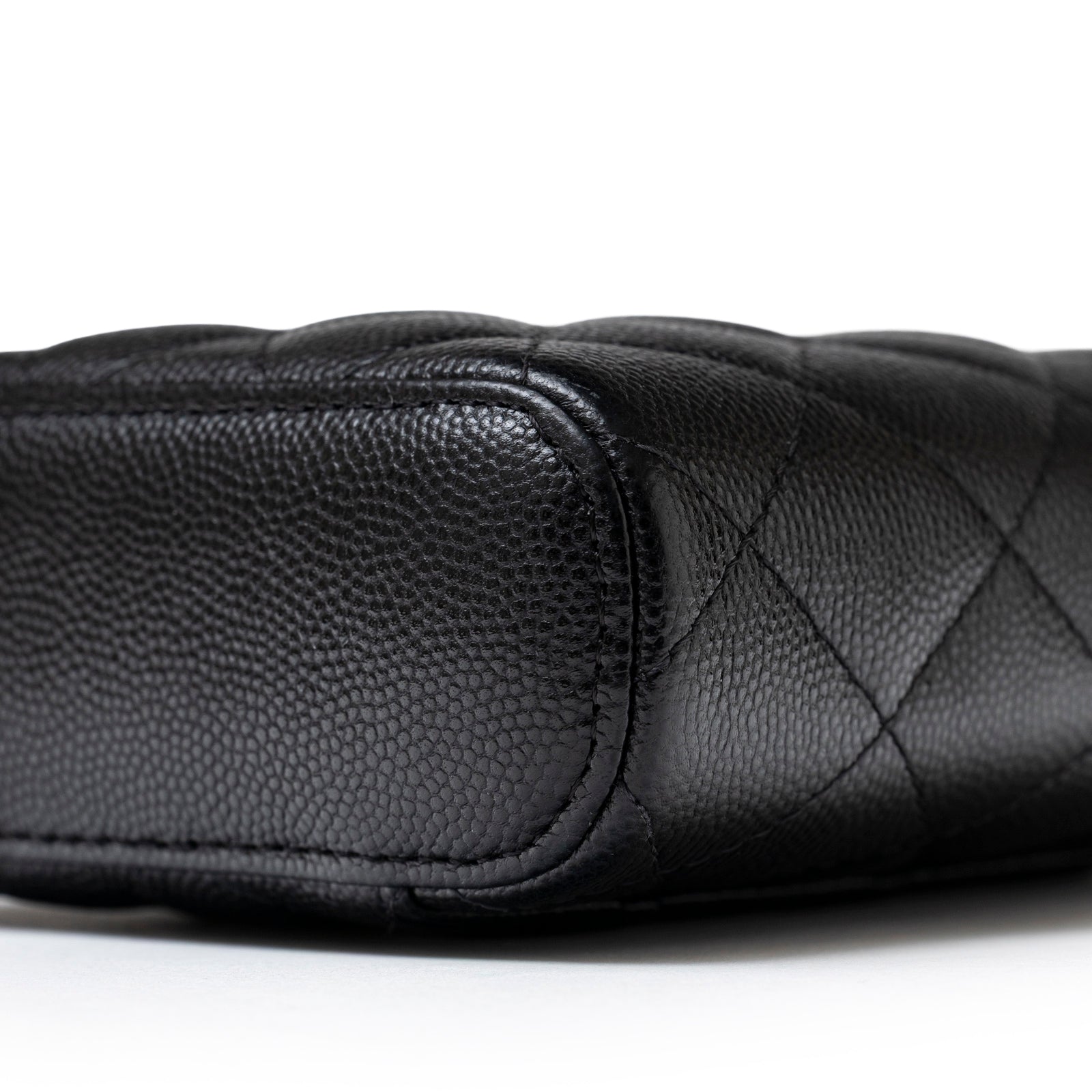 Close-up bottom corner view of Chanel Mini Coco Beauty Vanity Case on Chain Black Caviar Gold Hardware showing textured leather and stitching details