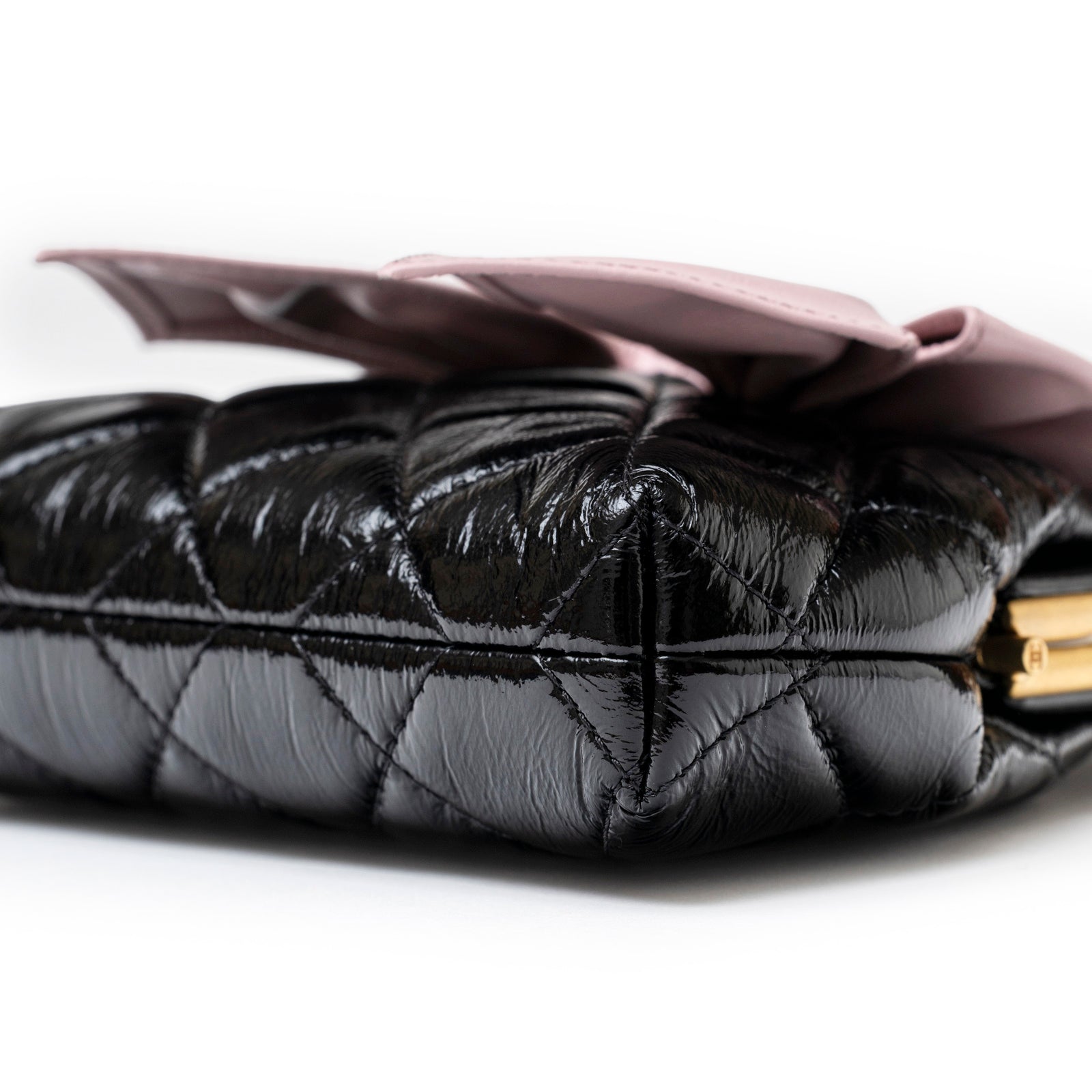 Close-up angled view of Chanel Maxi Bow Clutch With Chain Black/Pink Shiny Quilted Patent Crumpled Lambskin with brushed gold hardware edge detail