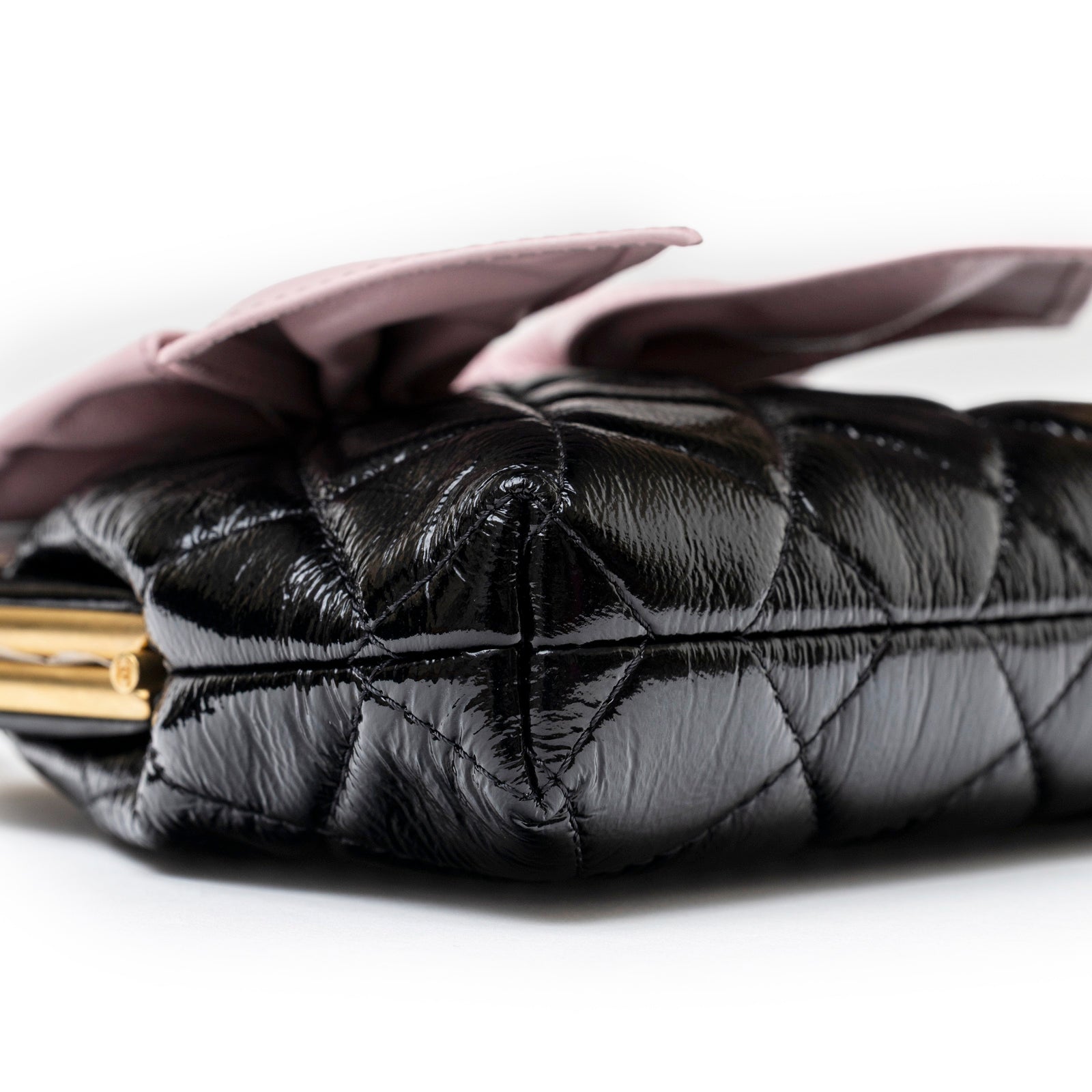 Close-up side view of Chanel Maxi Bow Clutch With Chain Black/Pink Shiny Quilted Patent Crumpled Lambskin Brushed Gold Hardware showing details