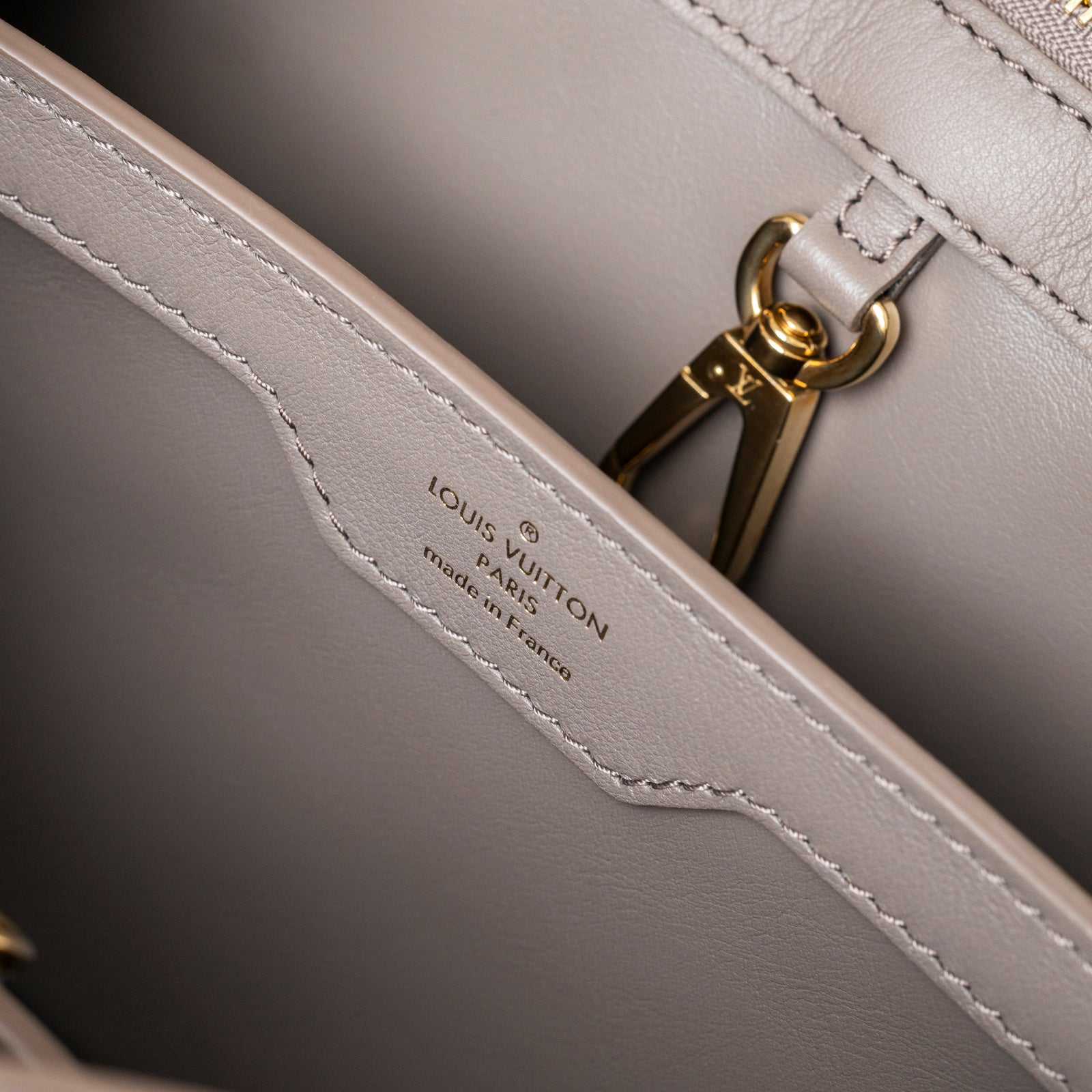 Close-up interior view of Louis Vuitton Since 1854 Embroidered Capucines BB Ecru/Taupe Calf Gold Hardware showing logo and gold clasp details