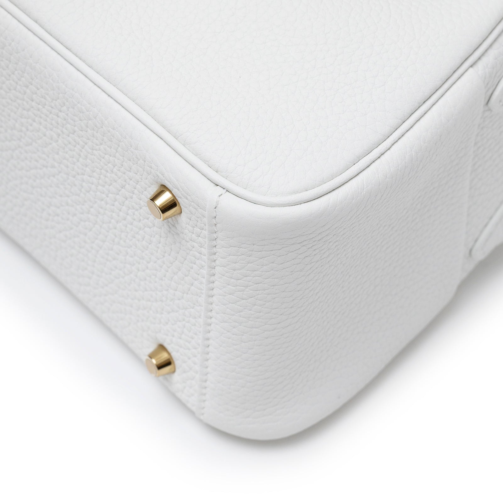 Close-up of bottom corner and gold hardware feet on Hermès Mini Lindy II New White Clemence Gold Hardware bag