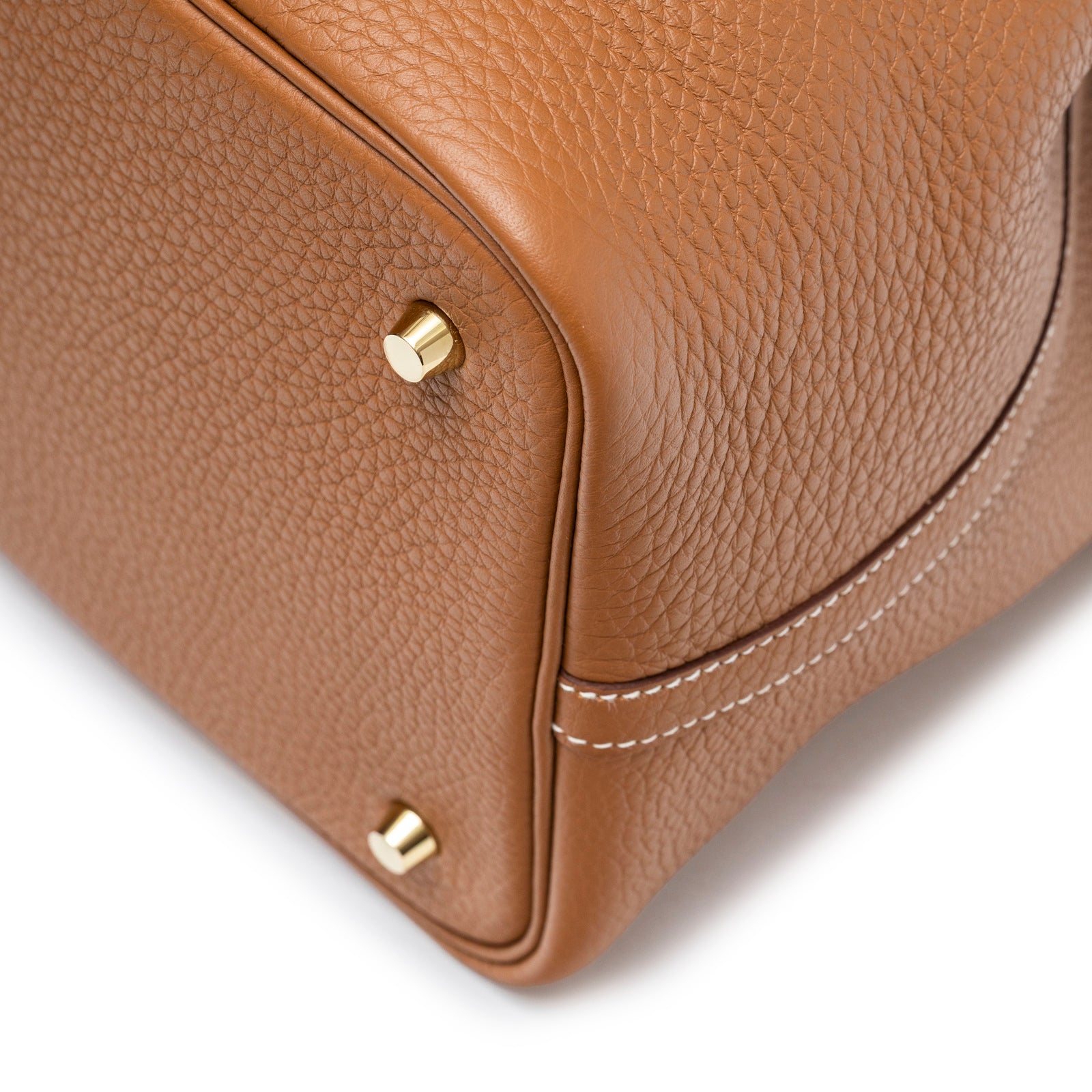 Close-up of bottom corner and hardware showing textured leather and stitching of Hermès Picotin 22 Gold Clemence Gold Hardware