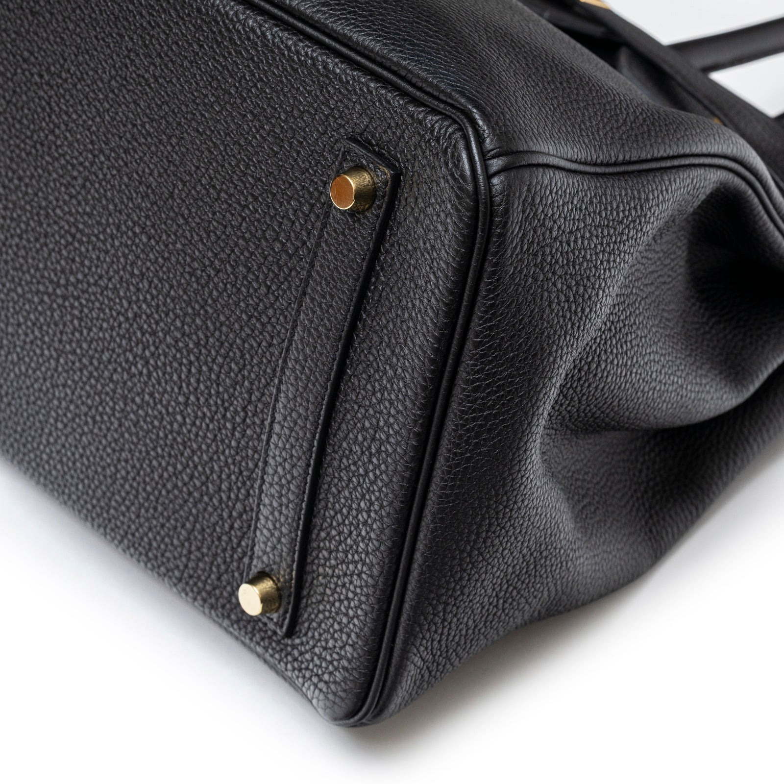 Close-up angled view of Hermès Birkin 35 Black Togo Gold Hardware bottom corner with protective feet and textured leather grain