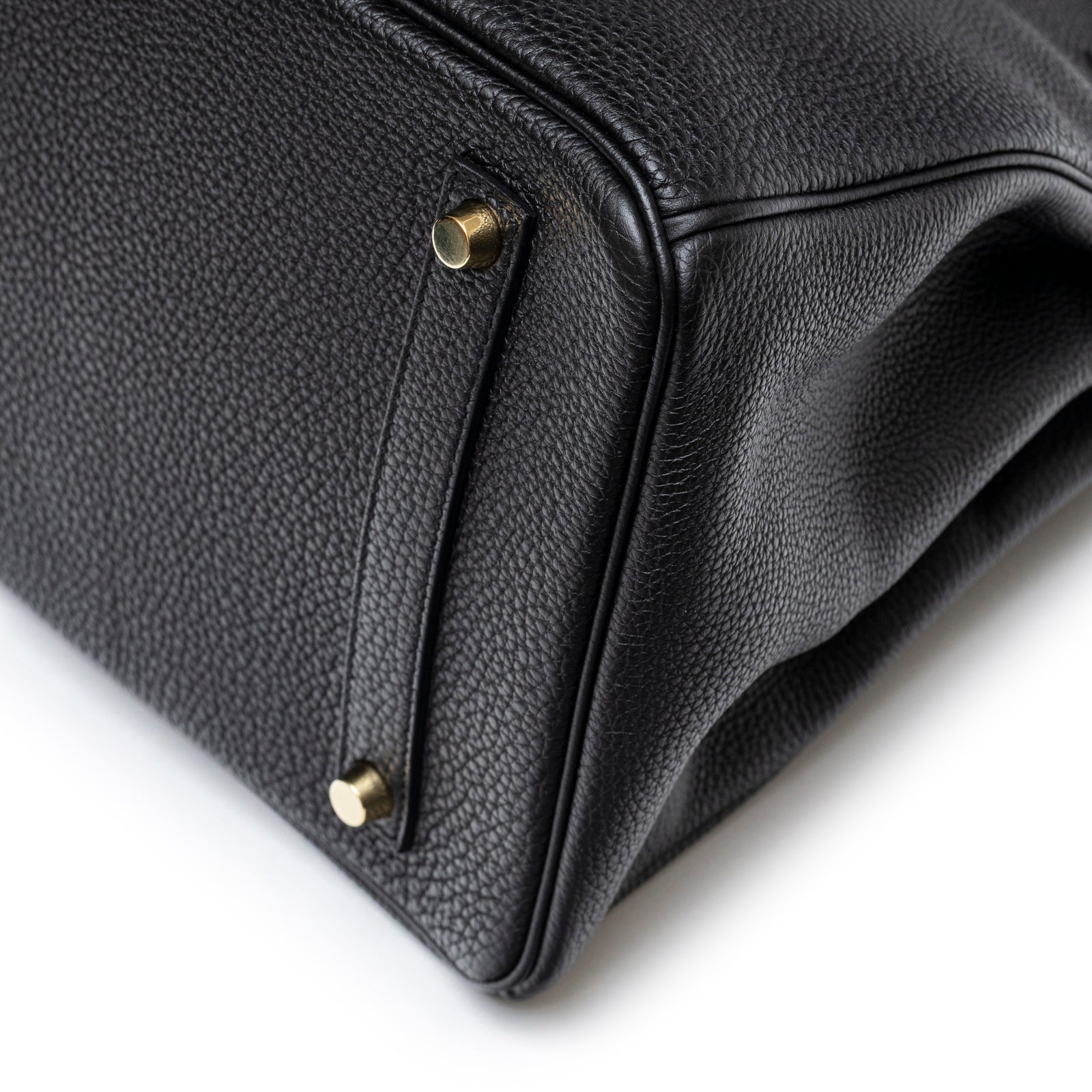Close-up angled view of Hermès Birkin 35 Black Togo Gold Hardware showing corner stitching and protective feet detail