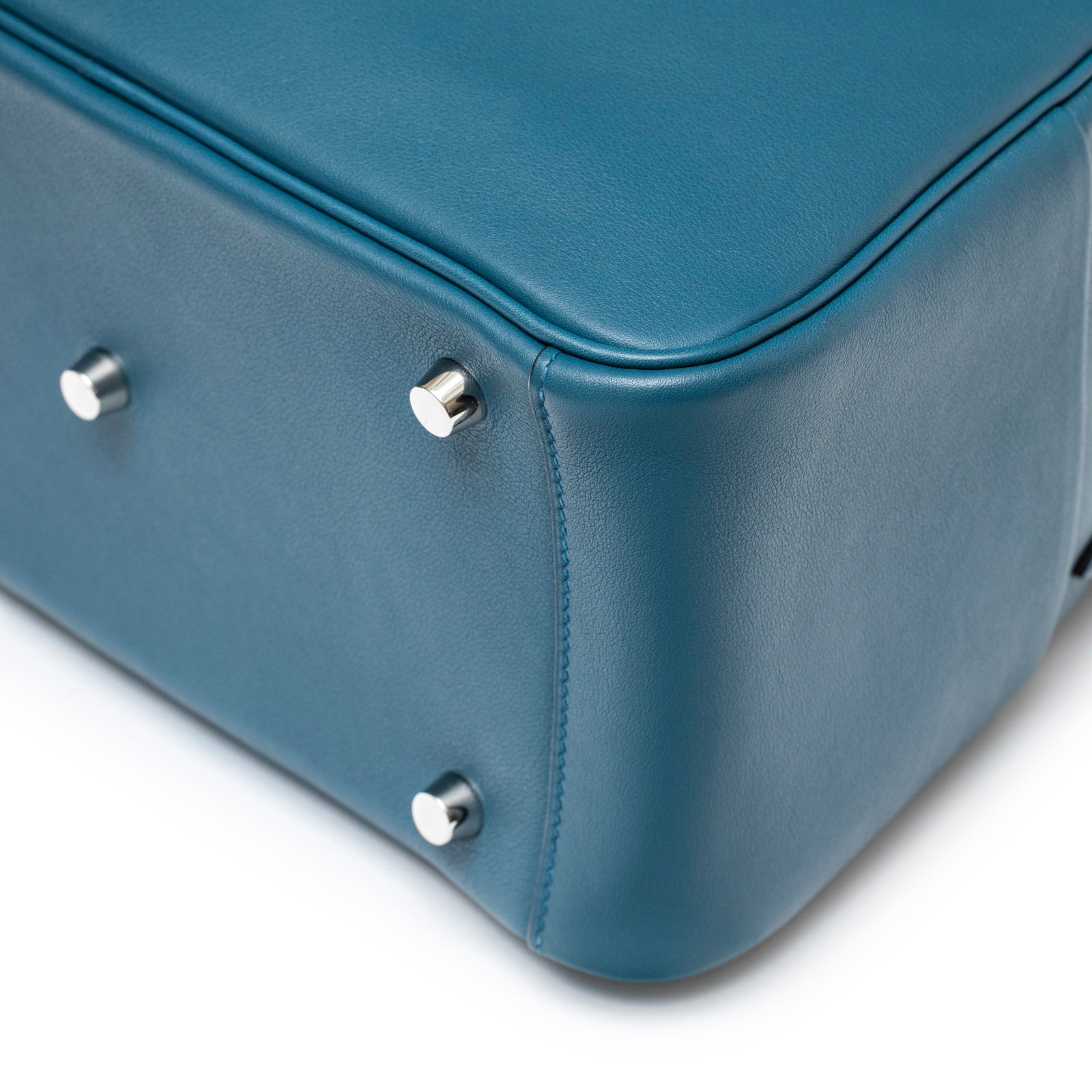 Close-up angled view of Hermès Lindy 26 Colvert Swift Palladium Hardware bottom corner with protective feet and smooth leather