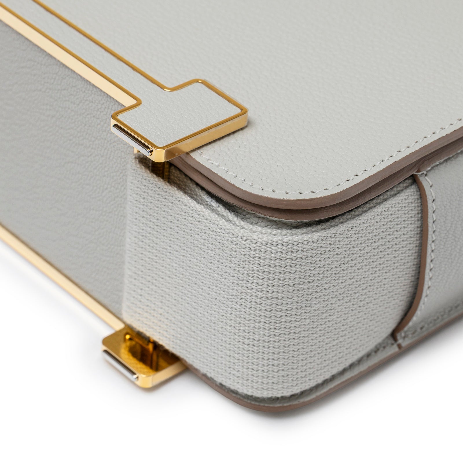 Close-up of textured fabric and gold hardware corner on Hermès Geta Gris Perle Chevre Mysore Gold Hardware bag