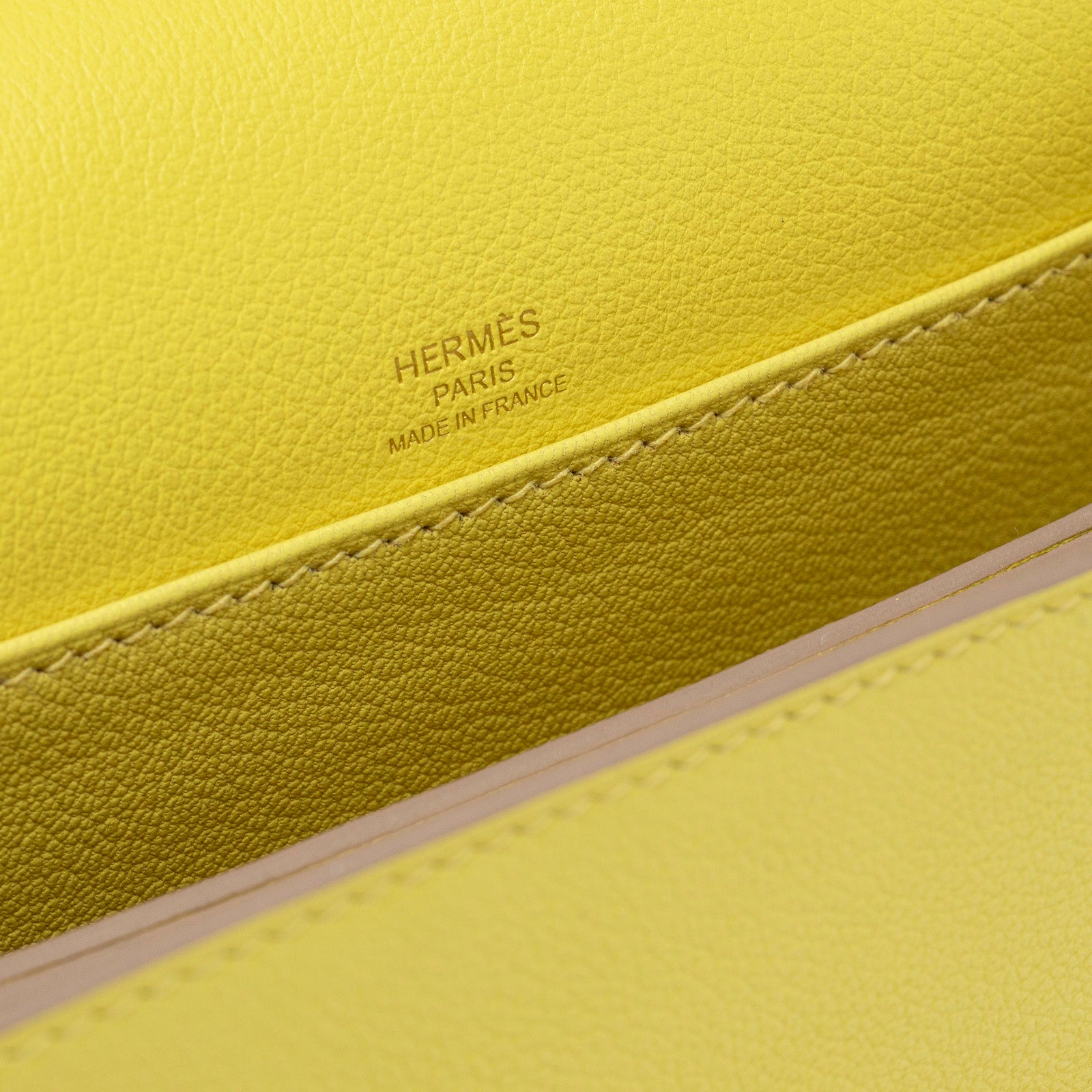 Close-up of Hermès Mini Roulis Lime Evercolor Permabrass Hardware interior stamp and stitching detail in bright yellow leather