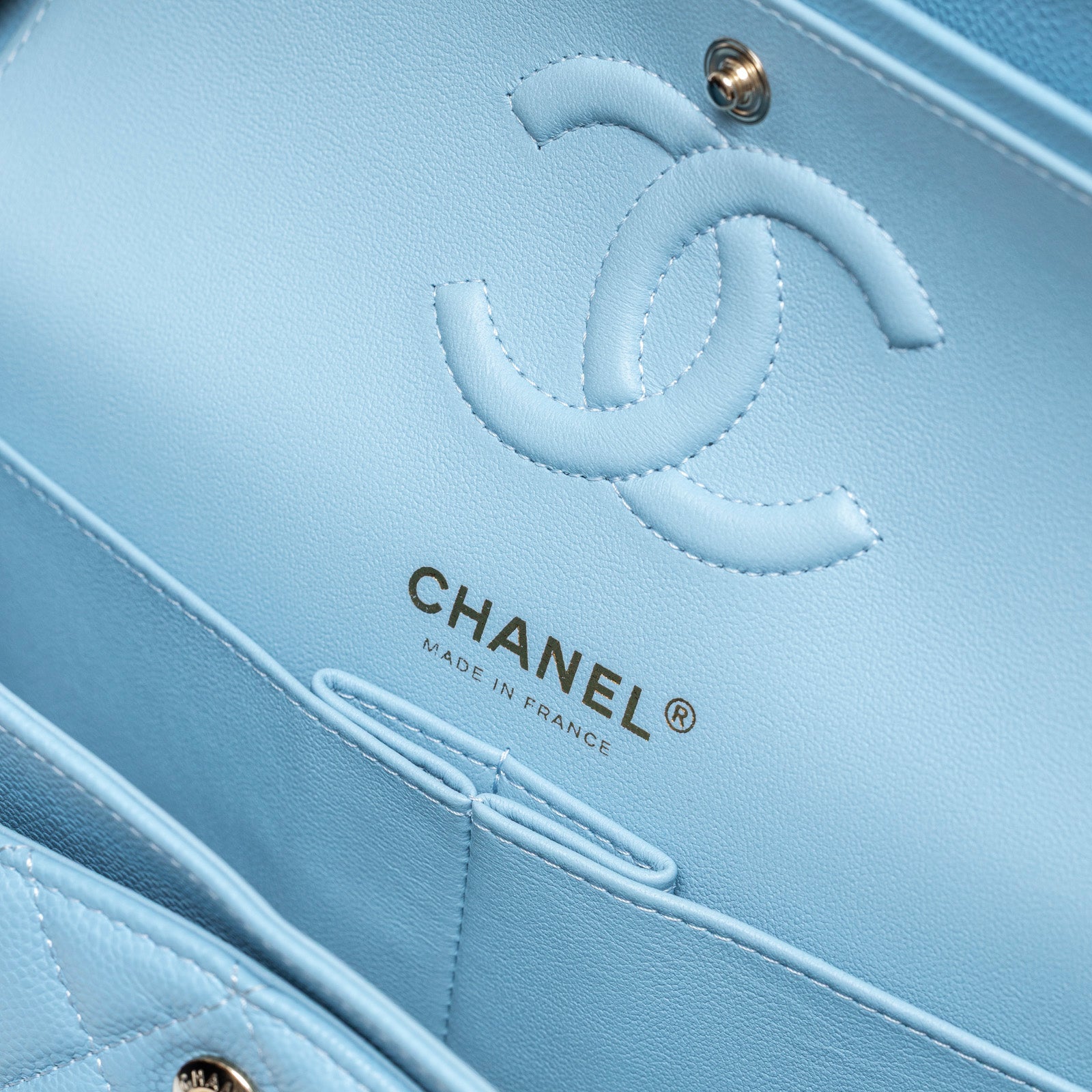 Close-up interior view of Chanel Small Classic Flap Bag Blue Caviar Light Gold Hardware showing logo and stitching detail