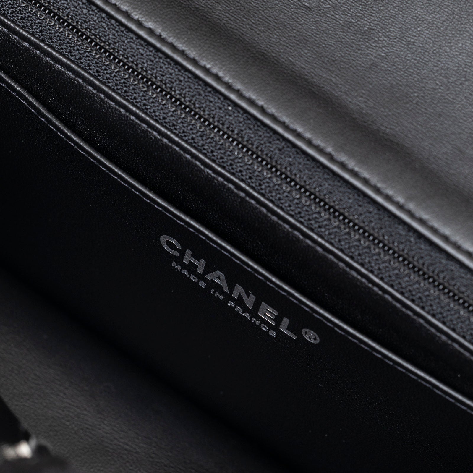 Close-up interior view of Chanel Mini Classic Flap Black and White Tweed Black Hardware showing logo and zipper detail