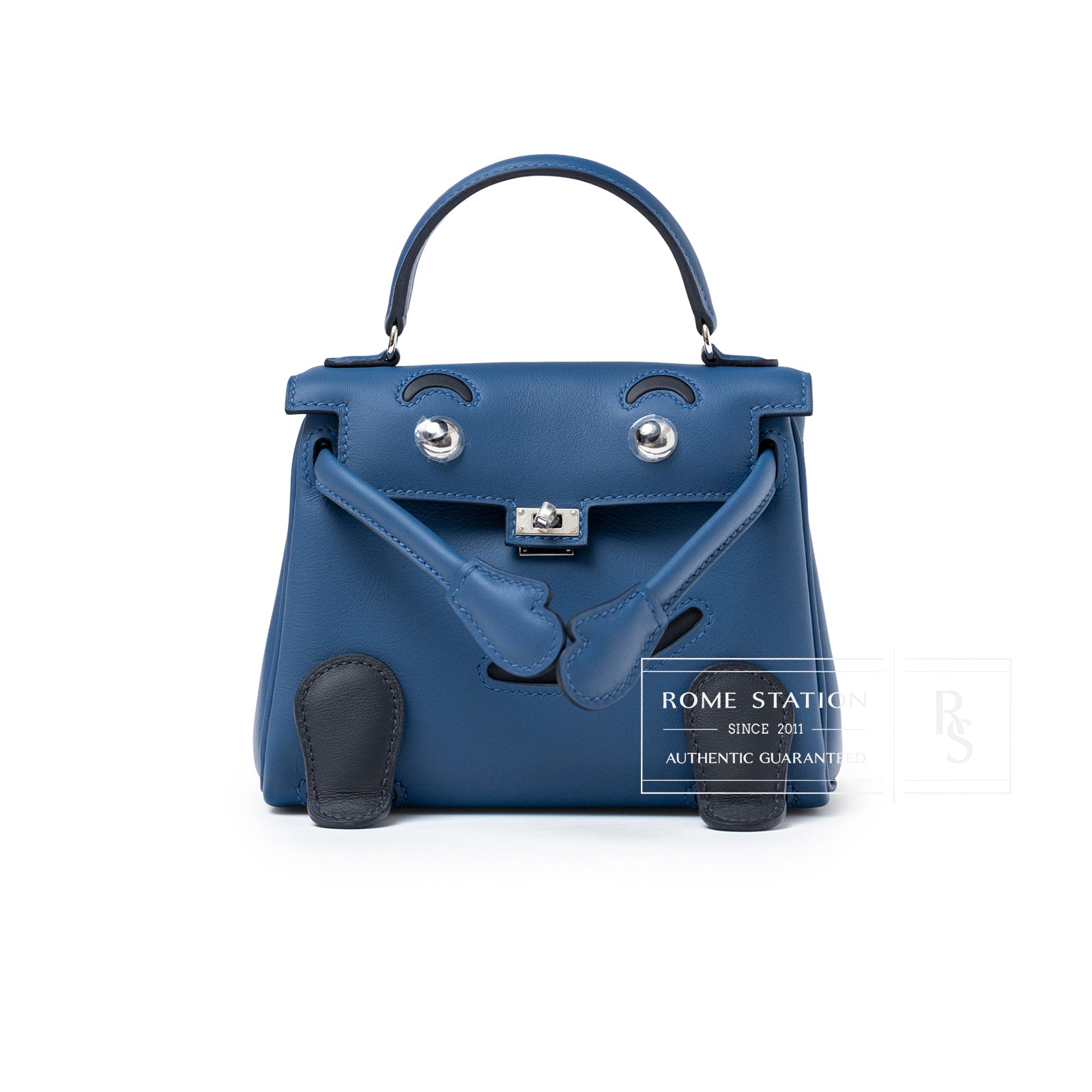 Front view of Hermès Quelle Idolle Kelly Doll Bleu Tie and Caban Swift Palladium Hardware with playful face detail