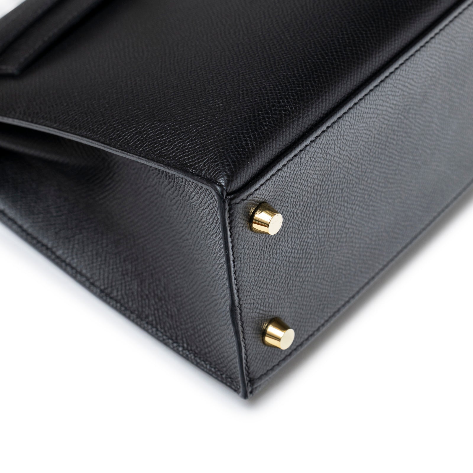 Close-up of bottom corner and gold hardware feet on Hermès Kelly Sellier 25 Black Epsom Gold Hardware bag