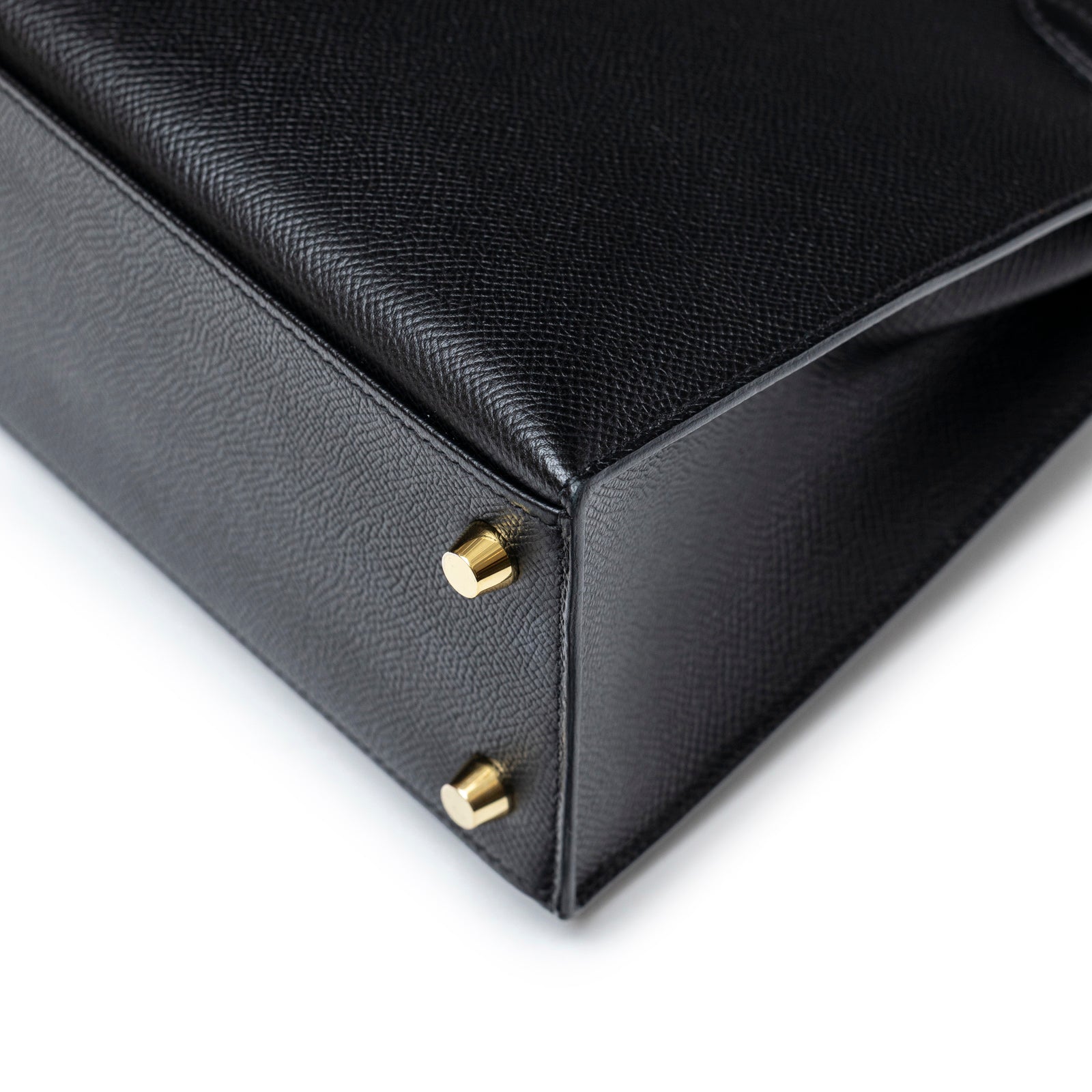Close-up of bottom corner and gold hardware feet on Hermès Kelly Sellier 25 Black Epsom Gold Hardware bag