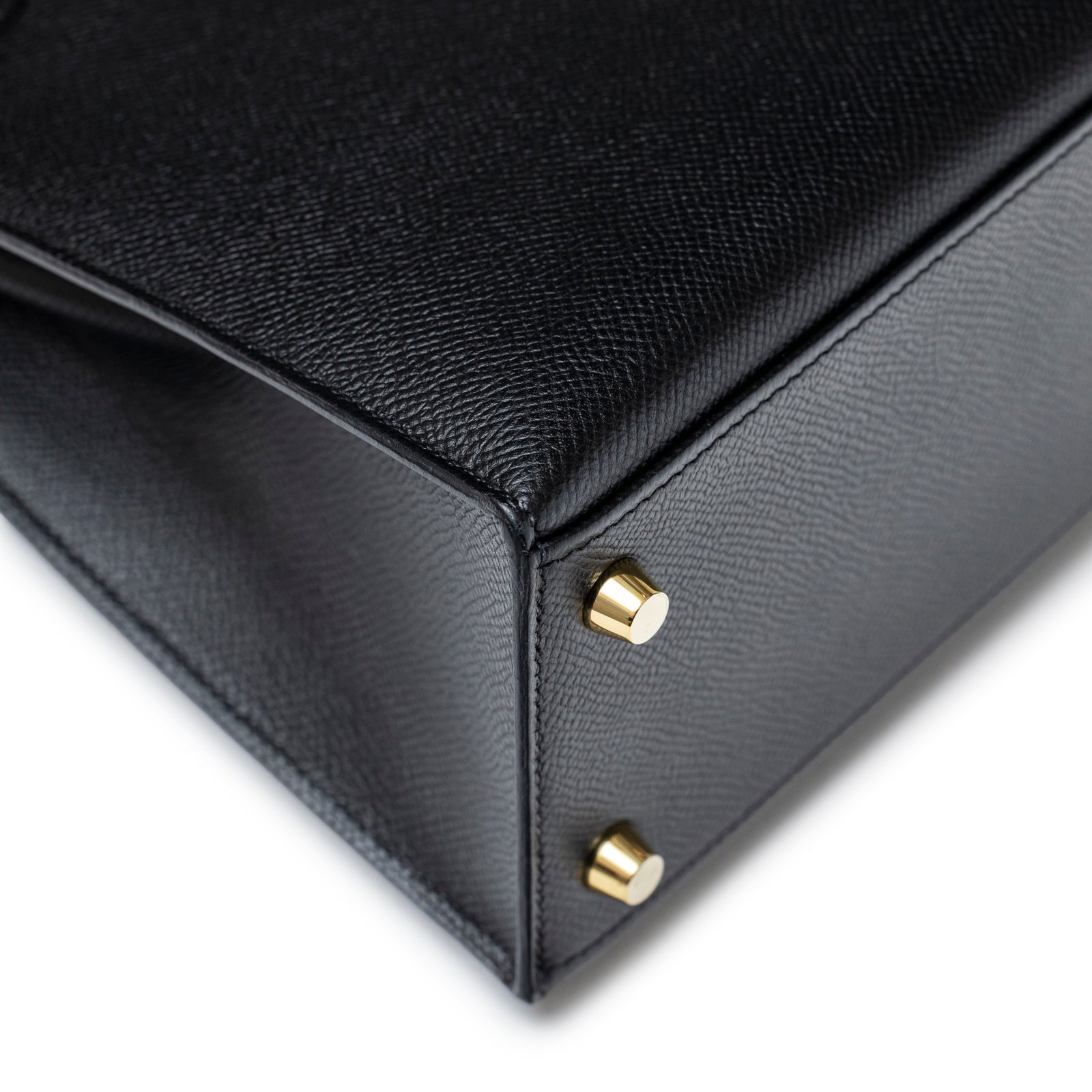 Close-up of bottom corner and gold feet hardware on Hermès Kelly Sellier 25 Black Epsom Gold Hardware bag