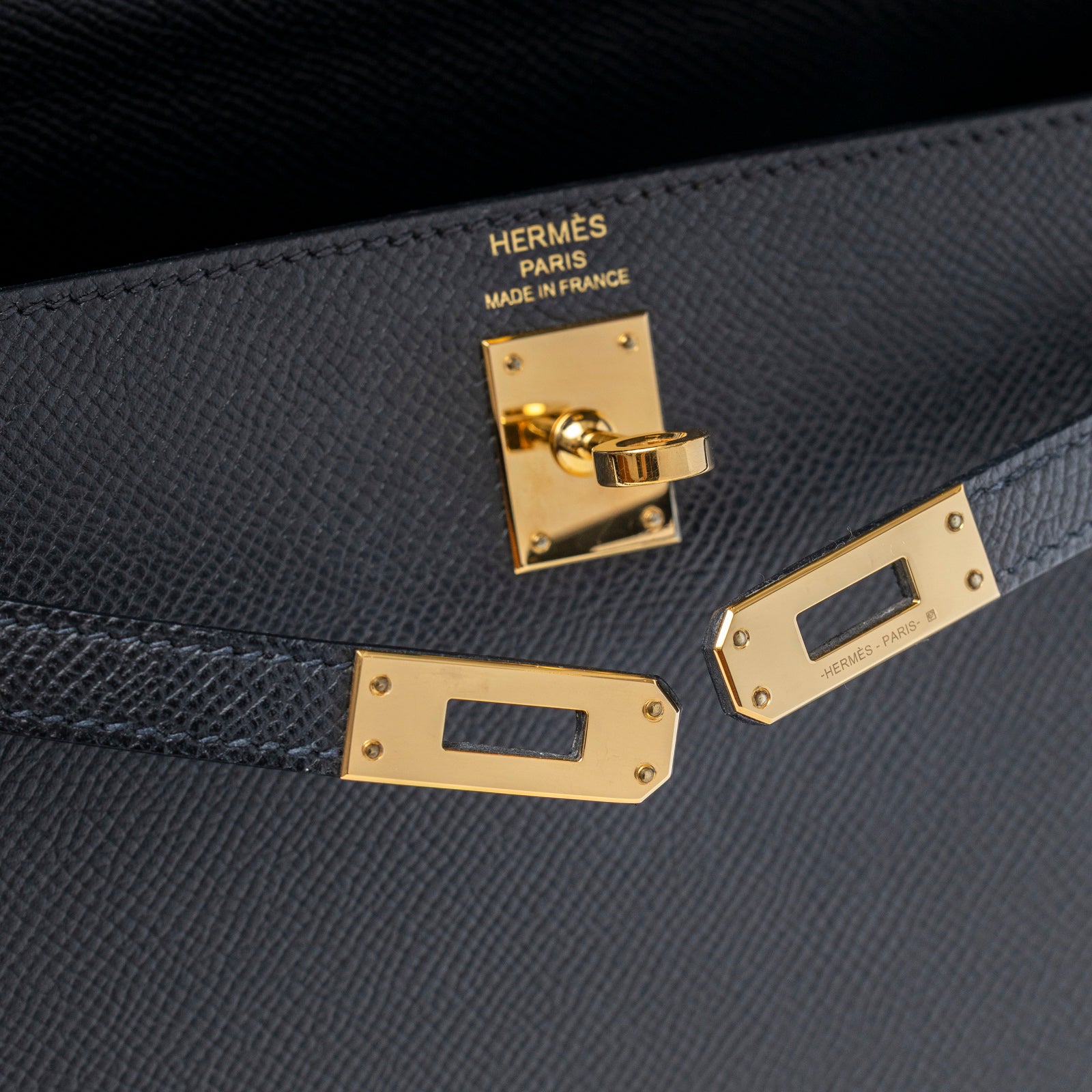 Close-up of gold hardware and black Epsom leather on Hermès Kelly Sellier 25 Black Epsom Gold Hardware bag interior lockplate