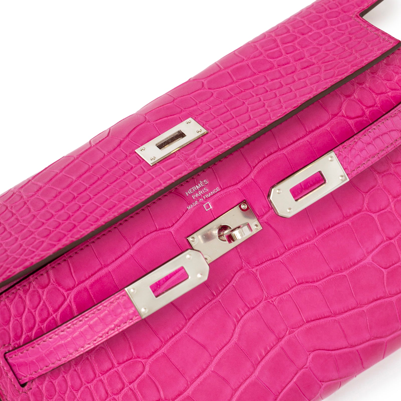 Close-up angled shot of Hermès Kelly Wallet To Go Rose Shocking Matte Alligator Palladium Hardware clasp and texture details