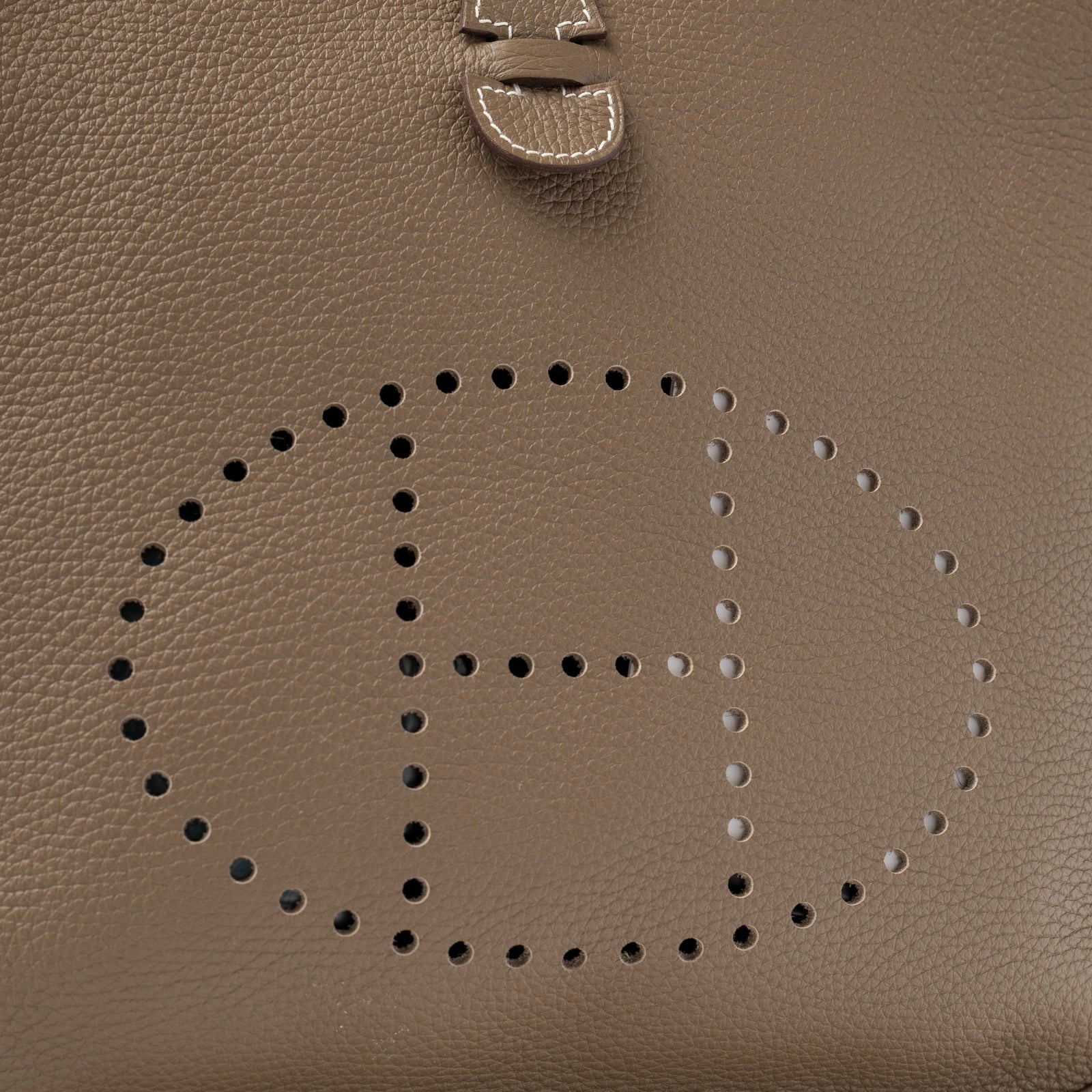 Close-up of Hermès Evelyne PM 29 Etoupe Clemence Palladium Hardware perforated H logo and textured leather detail