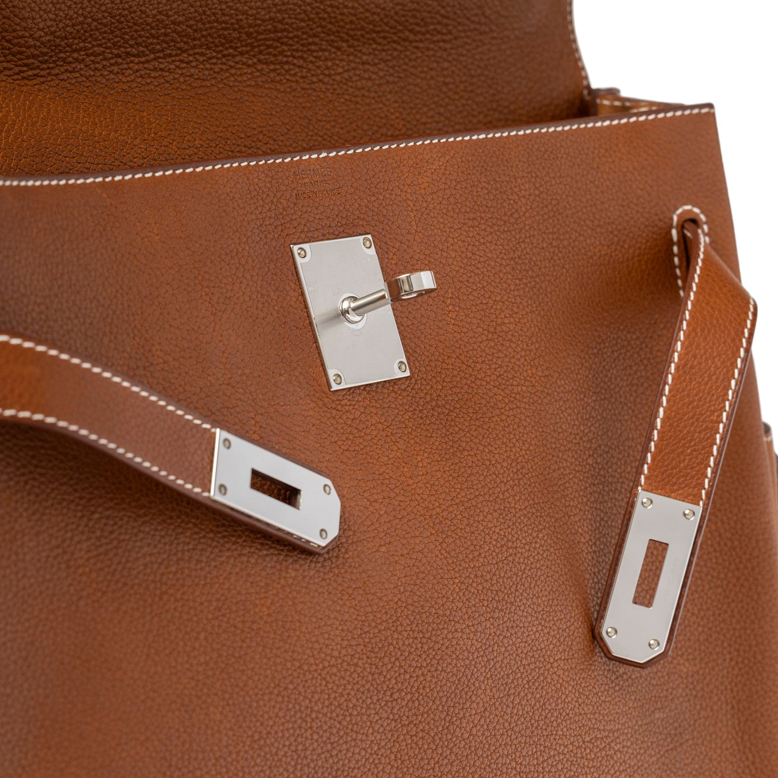 Close-up of Hermès Kelly Messenger GM Fauve Barenia Faubourg Palladium Hardware clasp and textured leather detail
