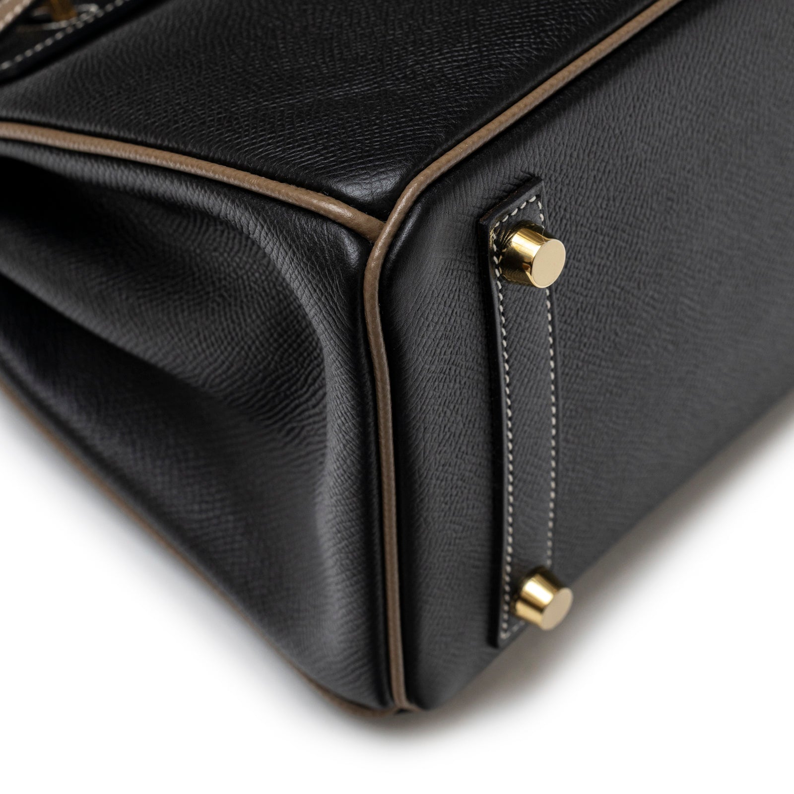 Close-up angled view of bottom corner with gold hardware and contrasting Etoupe piping on Hermès Special Order HSS Horseshoe Birkin 25 Black/Etoupe Epsom Gold Hardware
