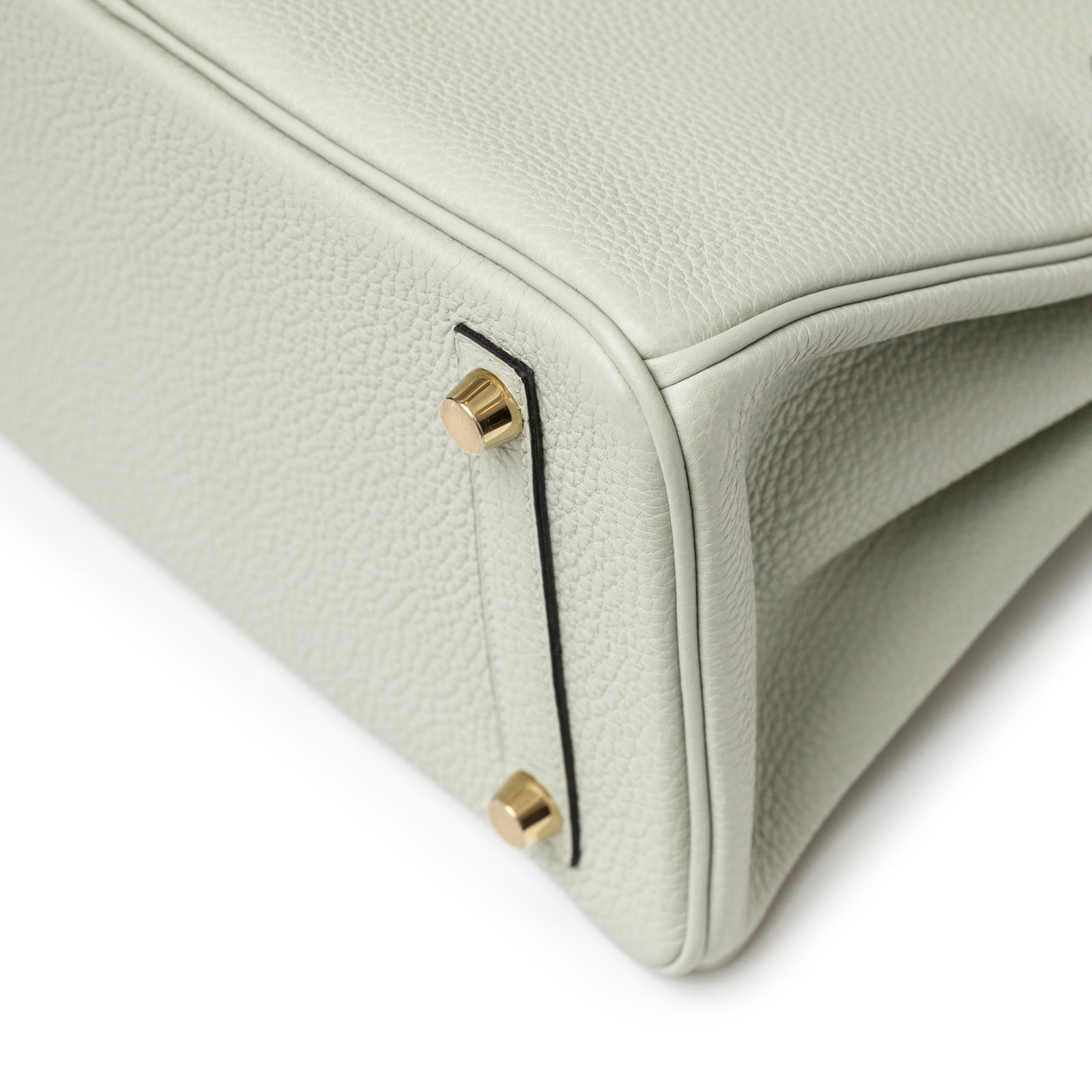 Close-up angled view of Hermès Birkin 25 Gris Neve Togo Gold Hardware leather bottom corner with gold studs