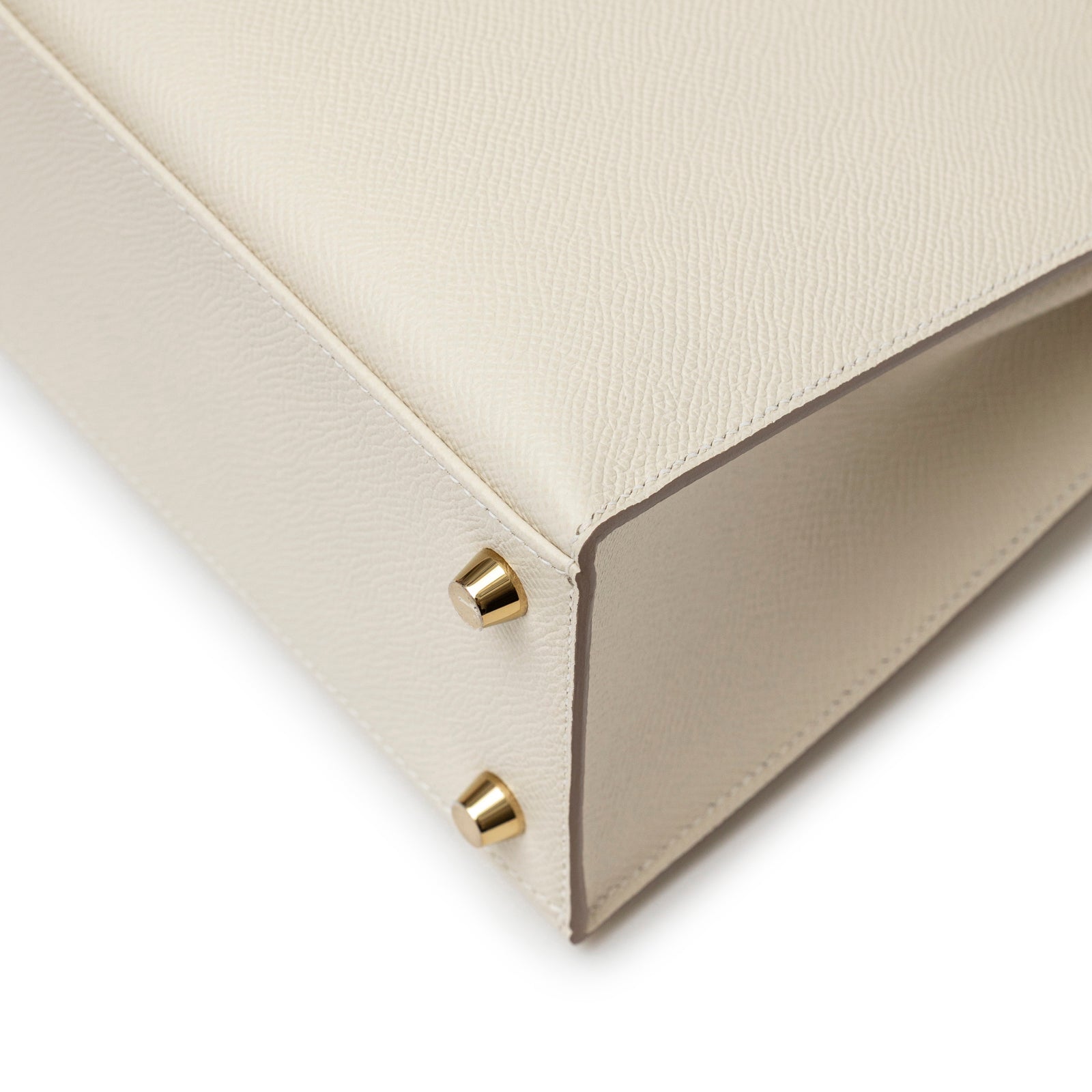 Close-up of beige Hermès Kelly 25 Sellier Epsom Craie Permabrass Hardware bottom corner with gold feet