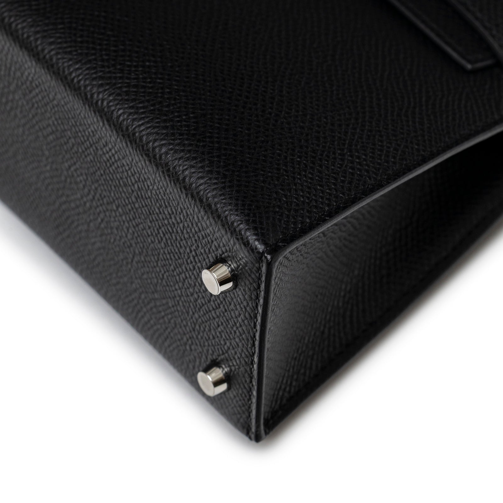 Close-up angled view of Hermès Mini Kelly II Sellier Black Epsom Palladium Hardware showing bottom corner feet and textured leather