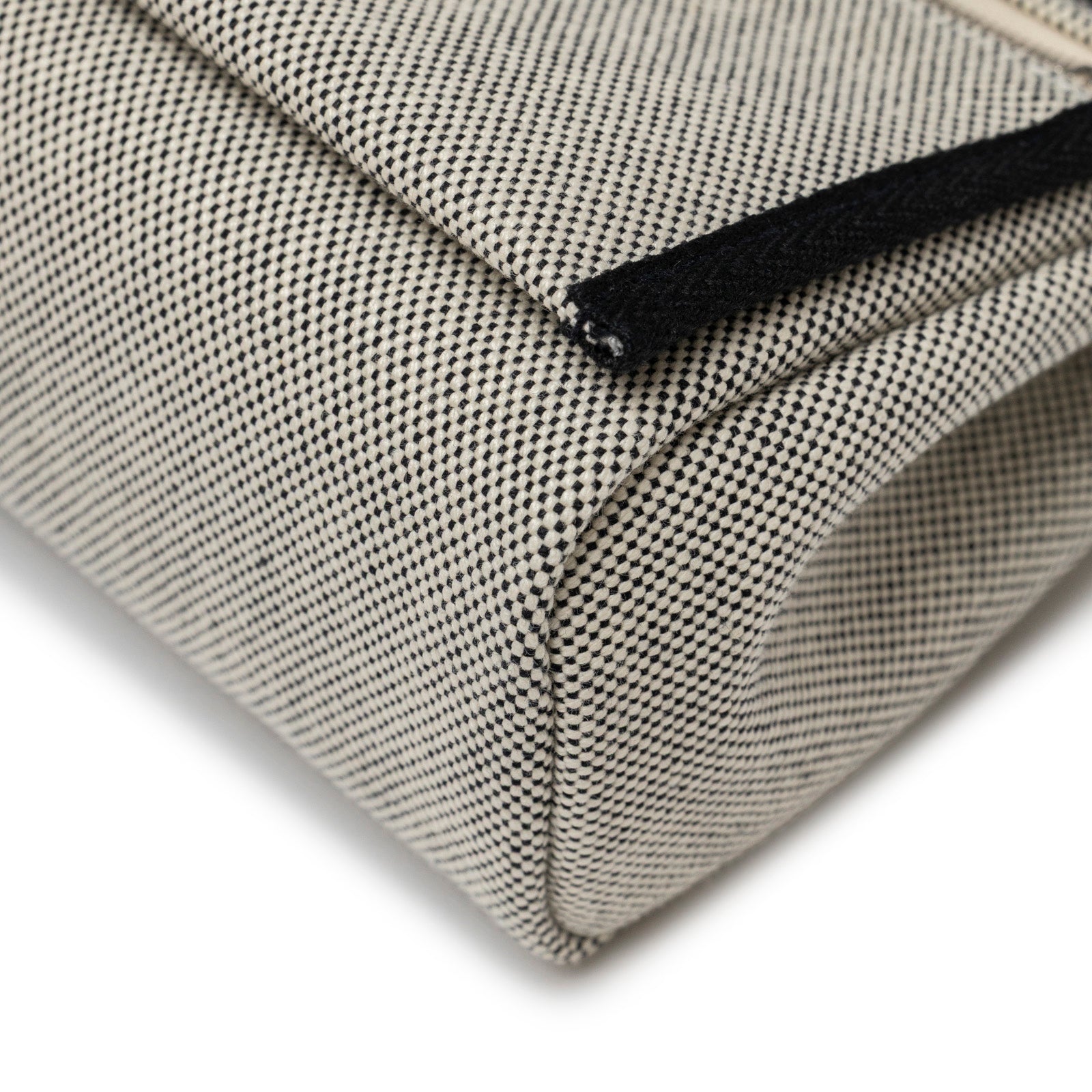 Close-up angled view of bottom corner and textured toile canvas of Hermès Mini Herbag Zip 20 Ecru/Black Toile and Vache Hunter Palladium Hardware