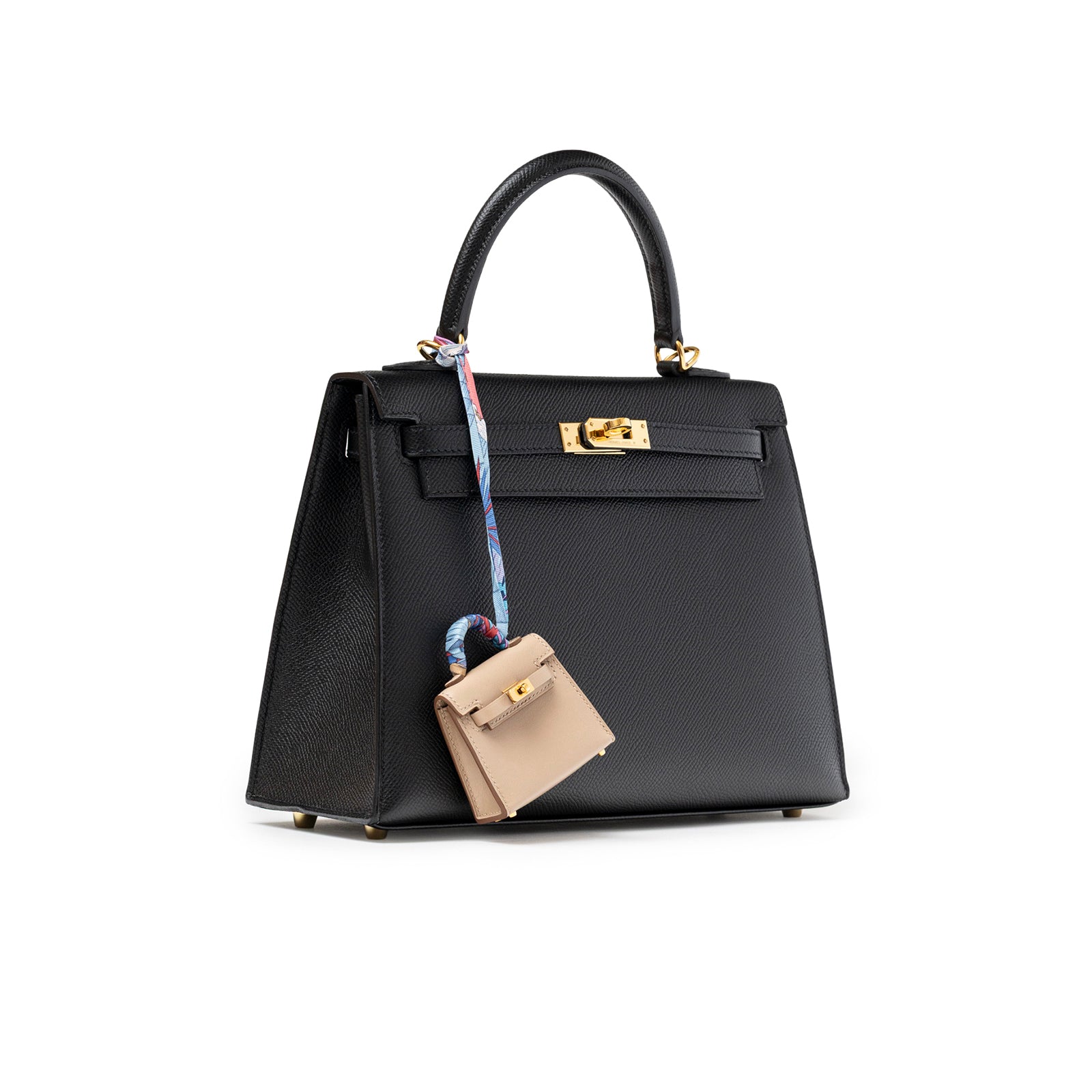 Angled view of black leather handbag with Hermès Mini Kelly Twilly Bag Charm Argile Tadelakt Gold Hardware attached