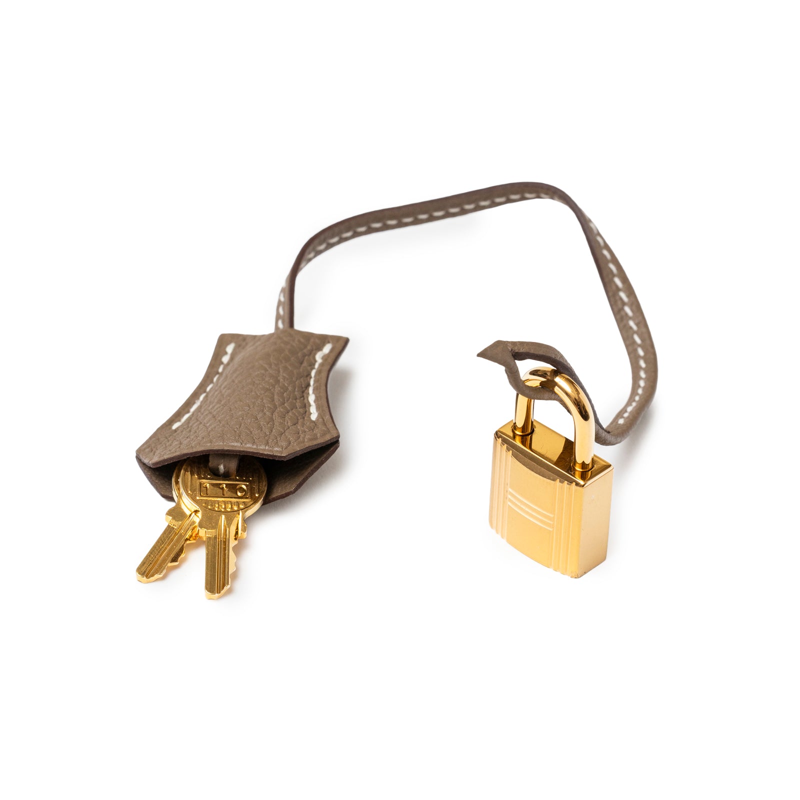 Close-up of Hermès Birkin 30 Etoupe Togo Gold Hardware gold lock and leather clochette with keys on white background