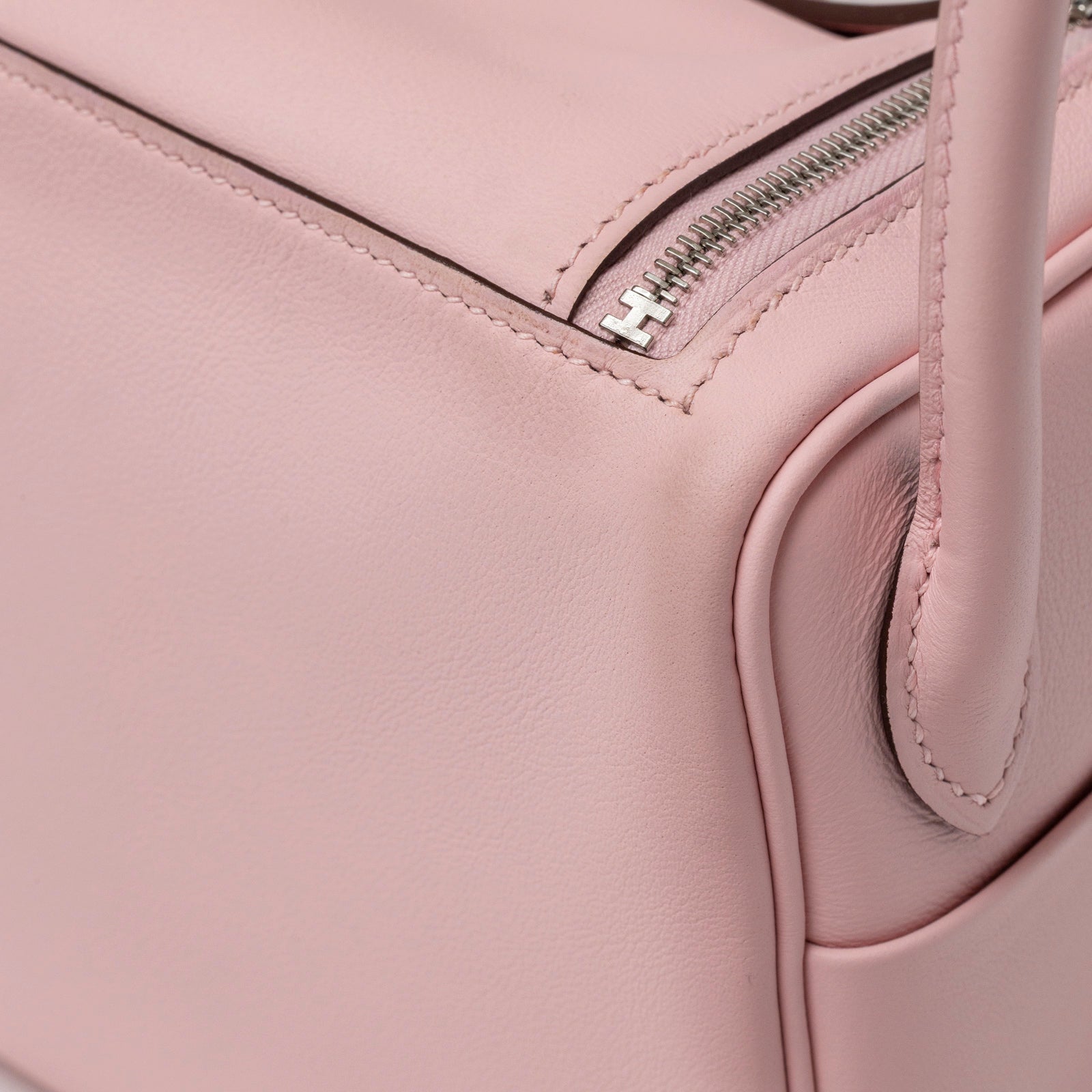 Close-up angled shot of Hermès Mini Lindy II Rose Sakura Swift Palladium Hardware corner and zipper detail