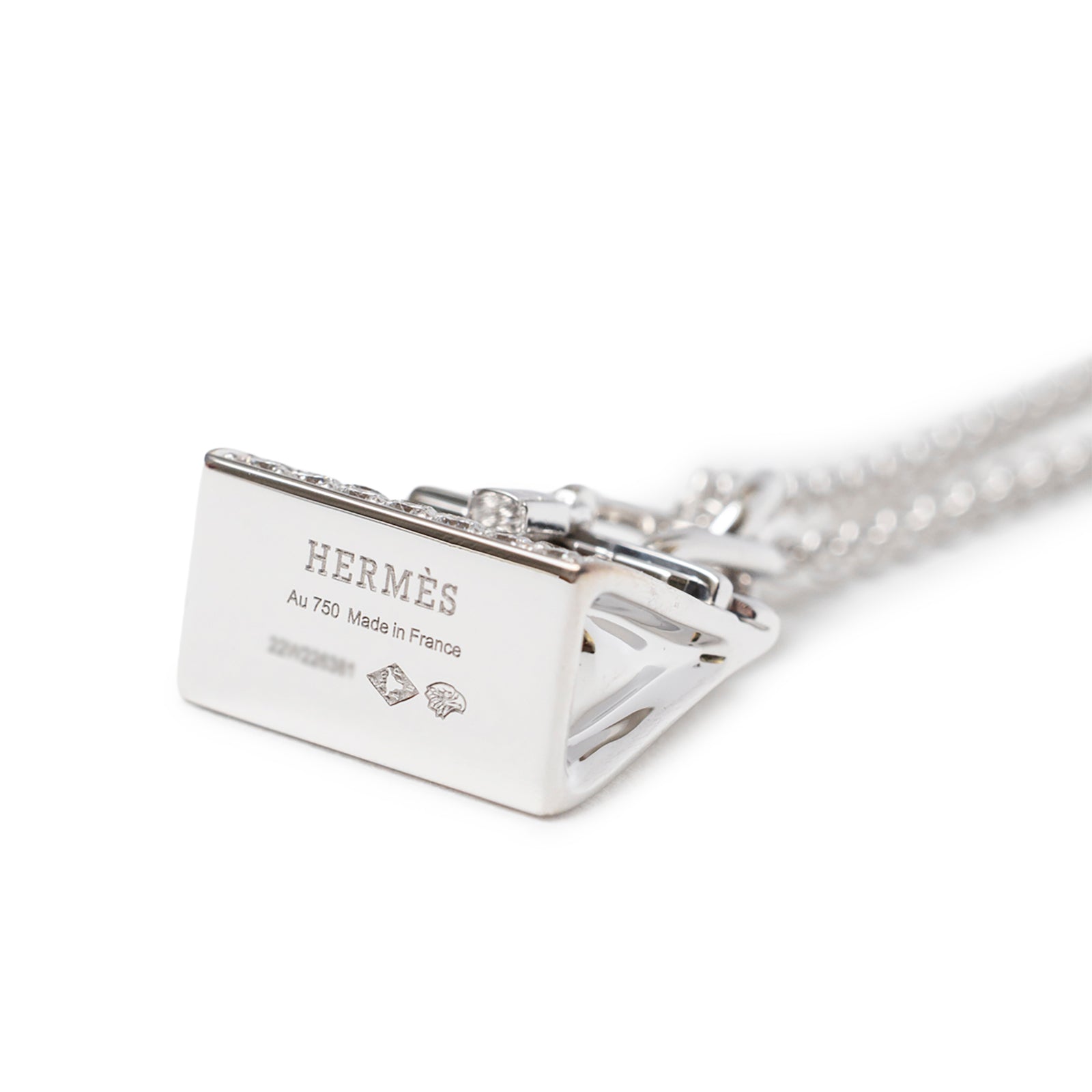 Close-up angled shot of Hermès Amulettes Birkin Pendant Diamonds and 18k White Gold hallmark and chain links