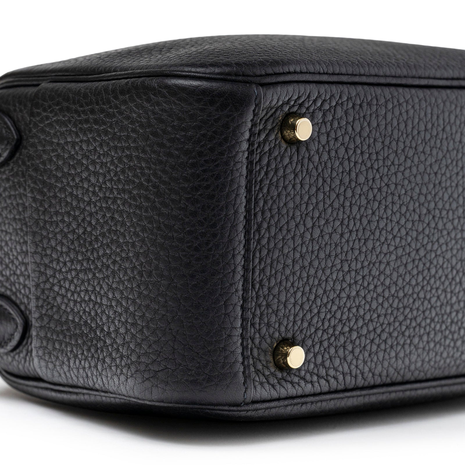 Close-up view of the bottom corner of Hermès Mini Lindy I Black Clemence Gold Hardware showing textured leather and gold feet