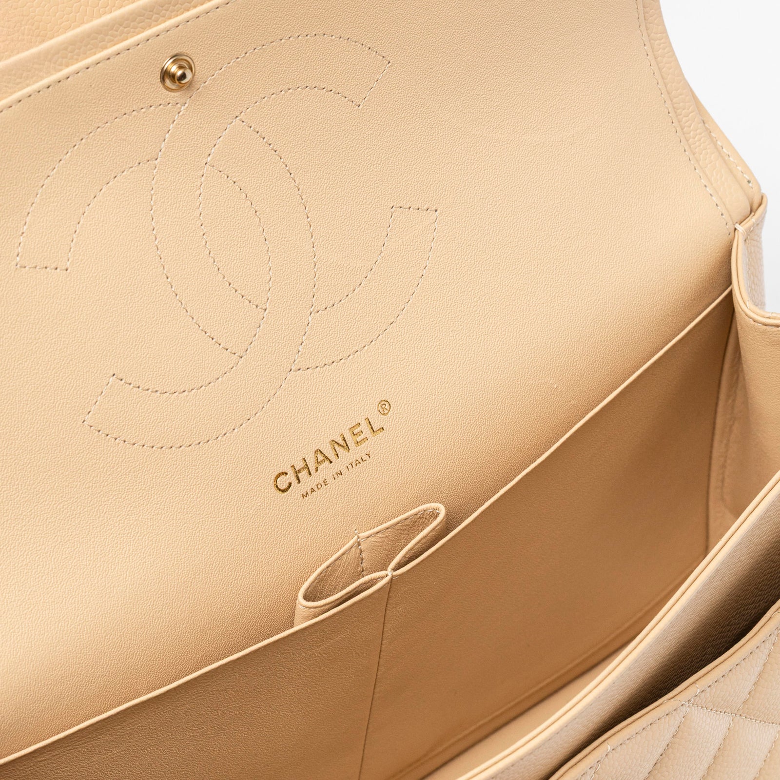 Close-up interior view of Chanel Classic Flap Jumbo Caviar Beige Gold Hardware showing logo and stitching details