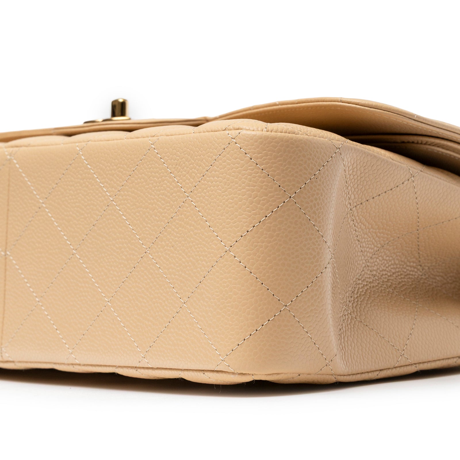 Close-up bottom corner view of Chanel Classic Flap Jumbo Caviar Beige Gold Hardware showing textured leather and quilted pattern