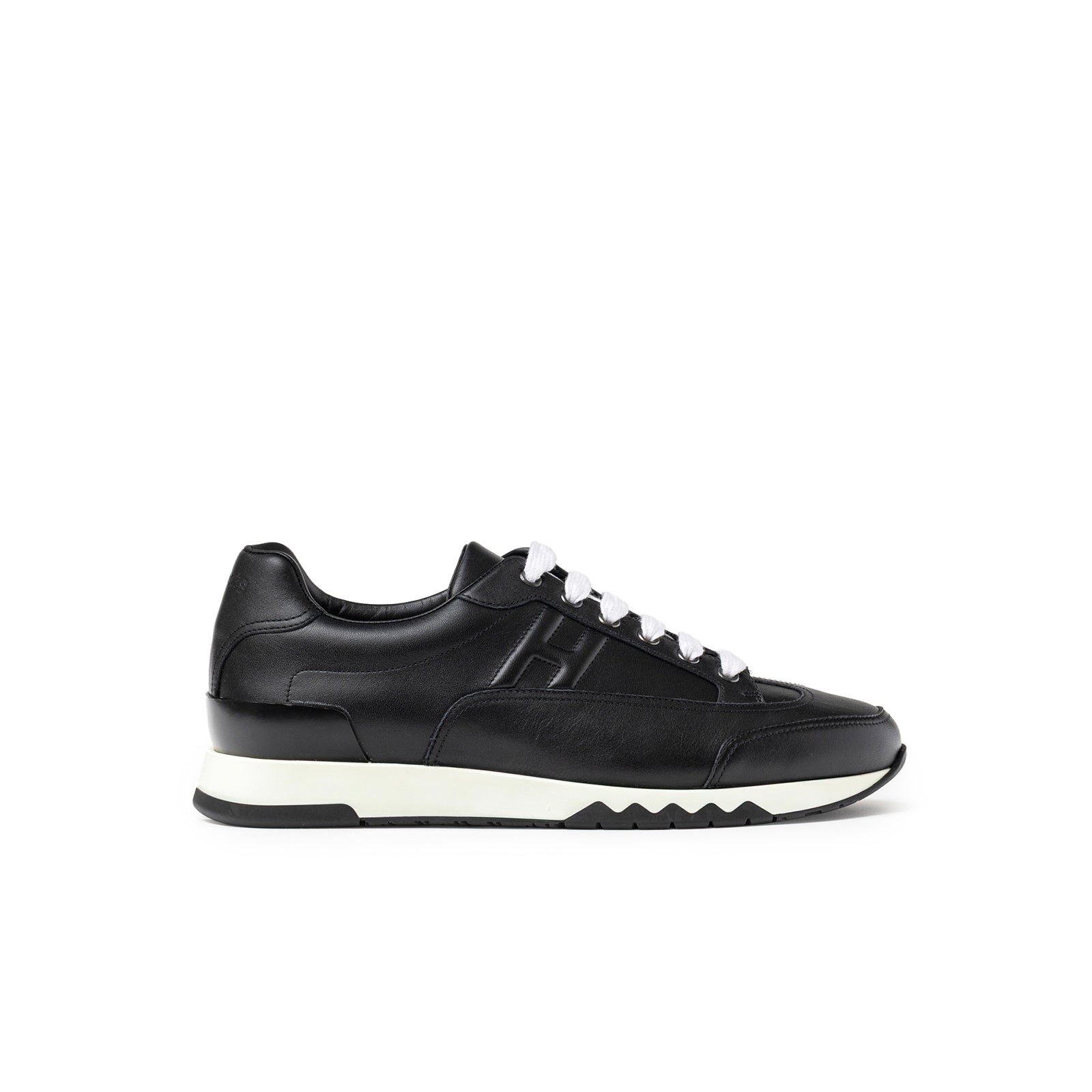 Side view of Hermès Men's Trail Sneaker Black in smooth black leather with white laces and a contrasting sole