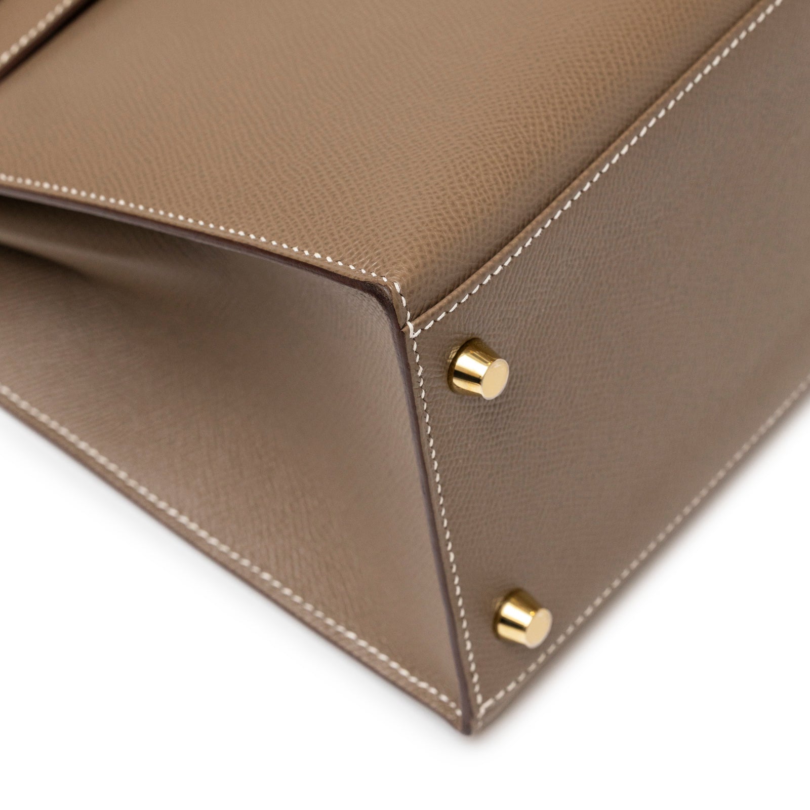 Close-up of corner stitching and gold hardware feet on Hermès Kelly 28 Sellier Etoupe Epsom Gold hardware handbag.