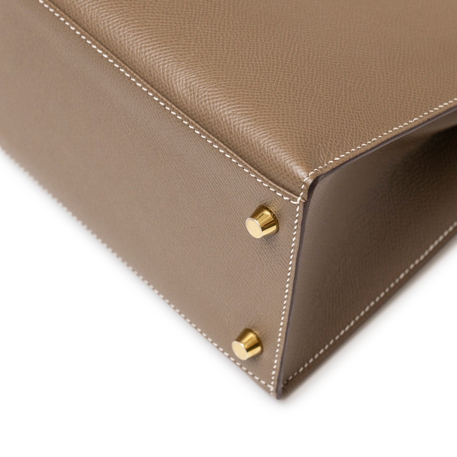 Close-up of bottom corner with gold hardware feet on Hermès Kelly 28 Sellier Etoupe Epsom Gold hardware handbag