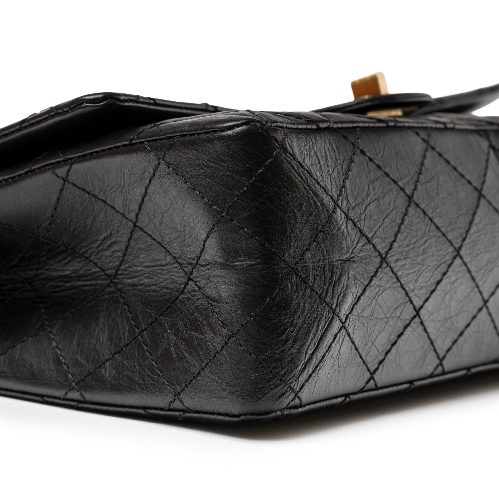 Close-up side view of the black aged calfskin and quilted texture on Chanel 2.55 Reissue 226 Flap Black Aged Calfskin Brushed Gold Hardware