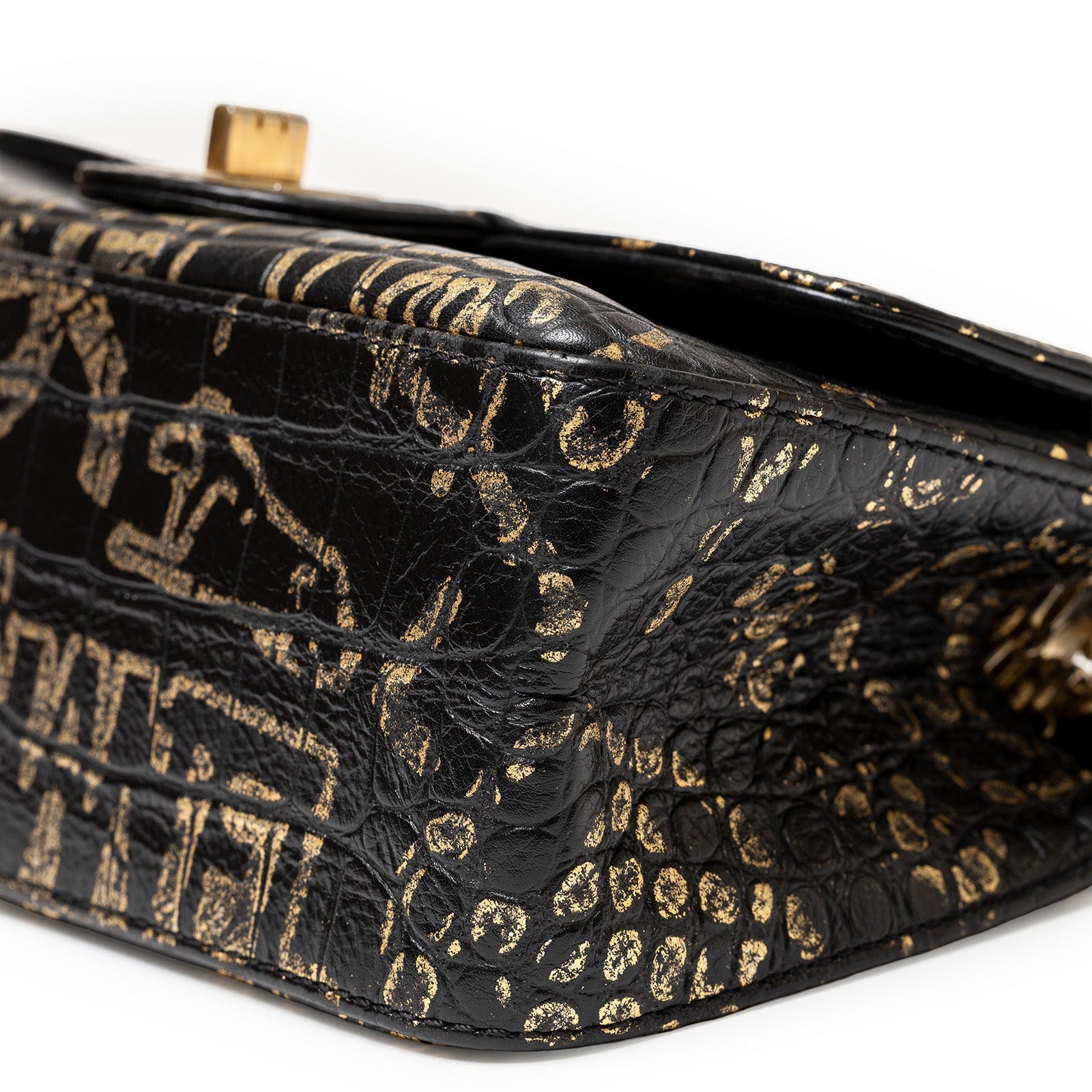 Close-up angled view of Chanel 2.55 Reissue 224 Flap Bag Black and Gold Graffiti Crocodile Embossed Calfskin Gold Hardware corner detailing