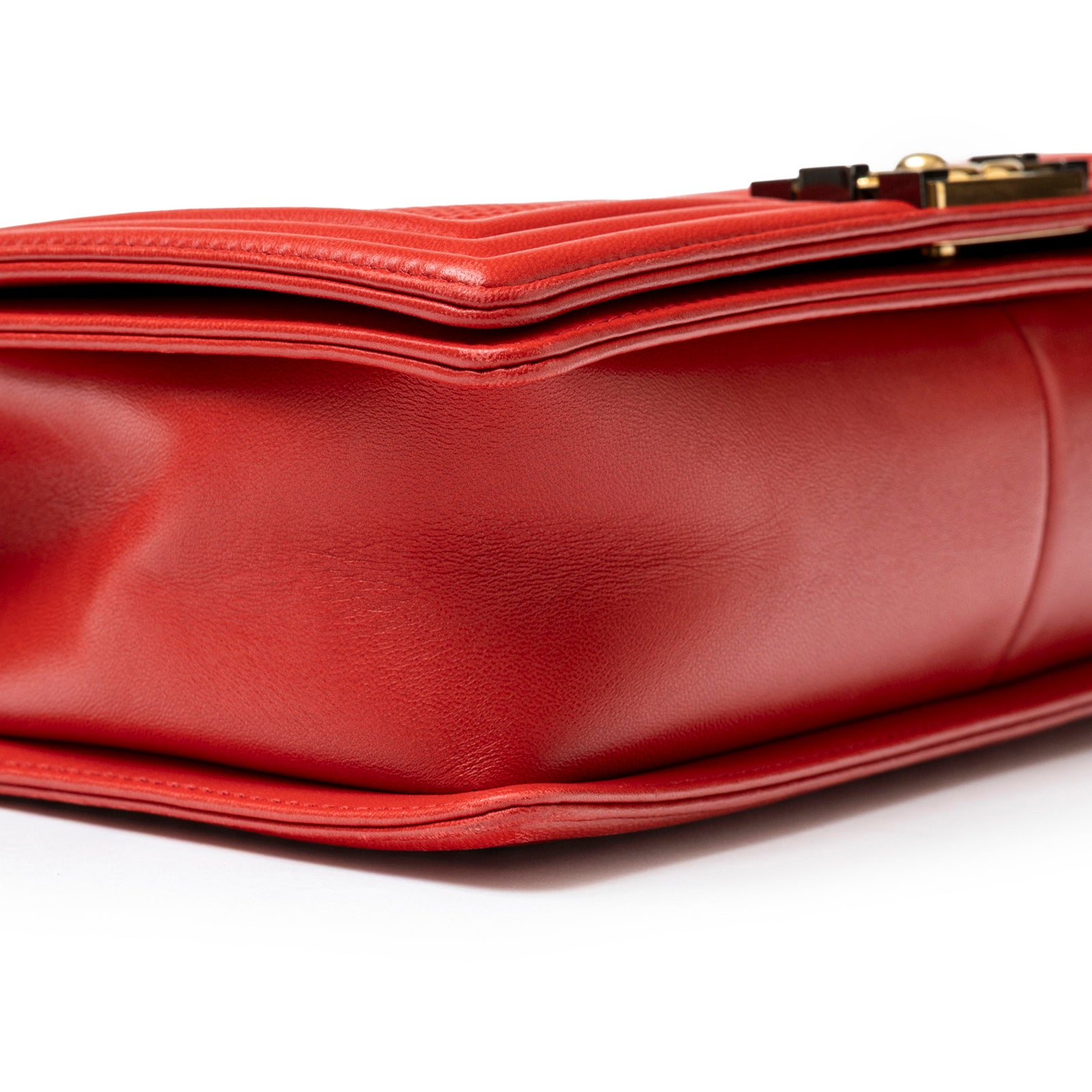 Close-up side view of red leather Chanel Leboy Flap Bag Coco Mark Waffle Bag Red White and Gold Hardware bottom corner details