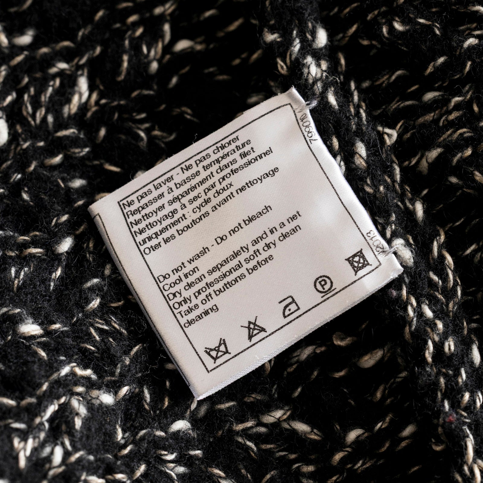 Close-up of care label sewn into textured fabric of Chanel Cardigan Long Black/White showing washing instructions.