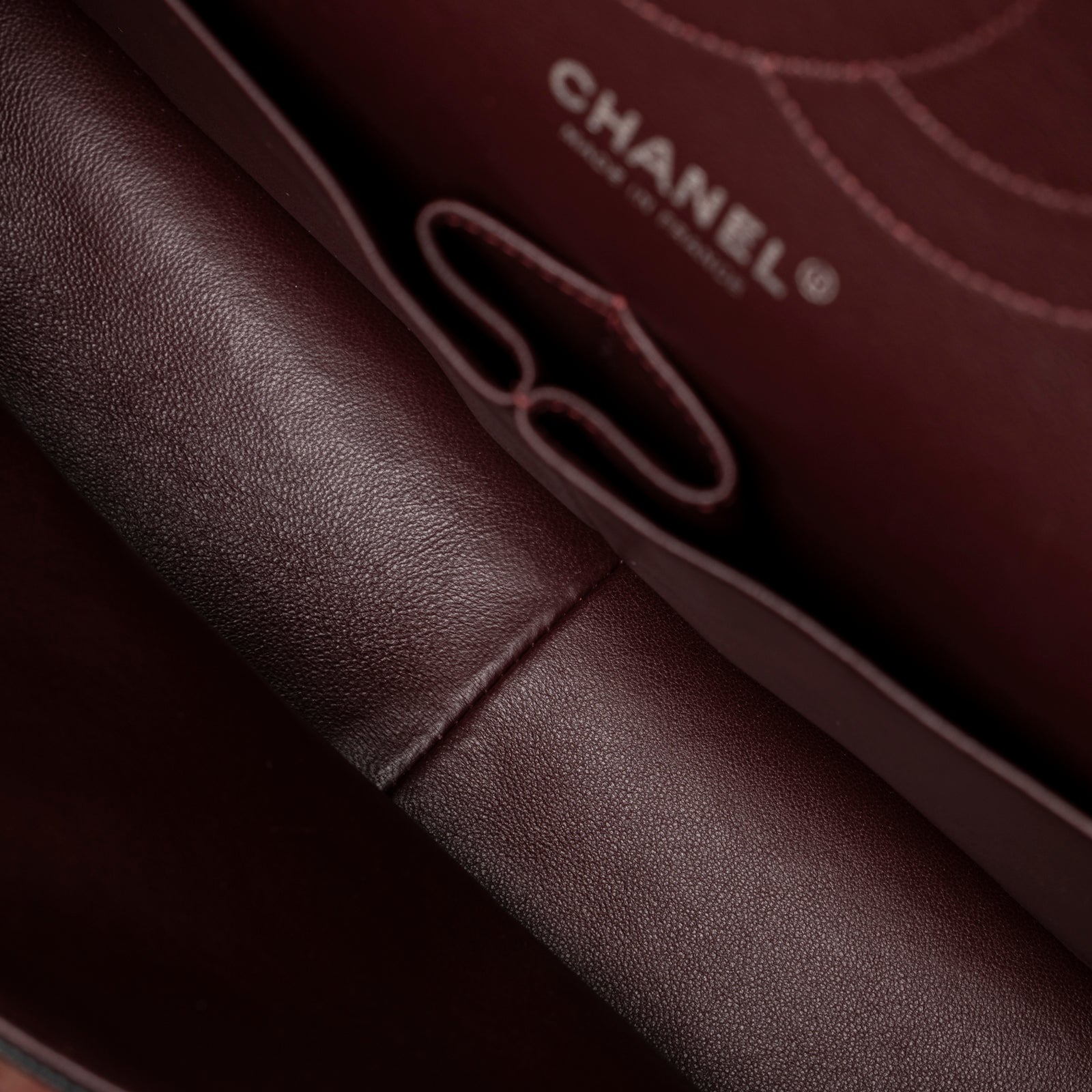Interior close-up of Chanel Jumbo Classic Double Flap Caviar Black Palladium Hardware showing burgundy leather lining and stitching detail