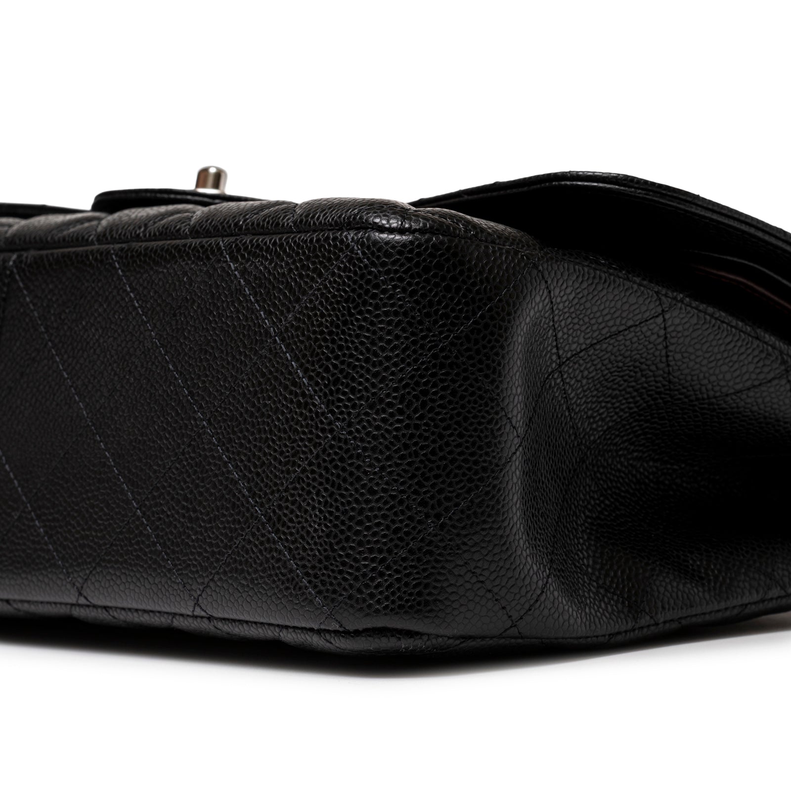 Close-up angled view of Chanel Jumbo Classic Double Flap Caviar Black Palladium Hardware bottom corner showing leather texture.