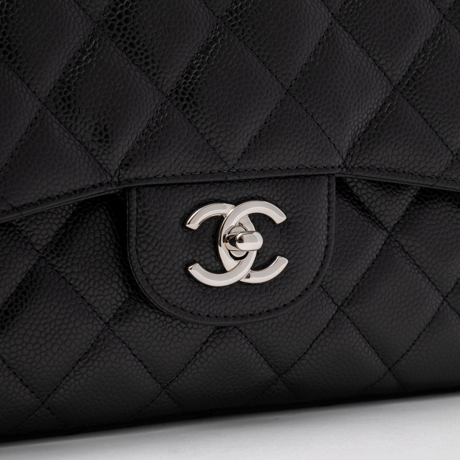 Close-up of the clasp on Chanel Jumbo Classic Double Flap Caviar Black Palladium Hardware showing quilted leather texture