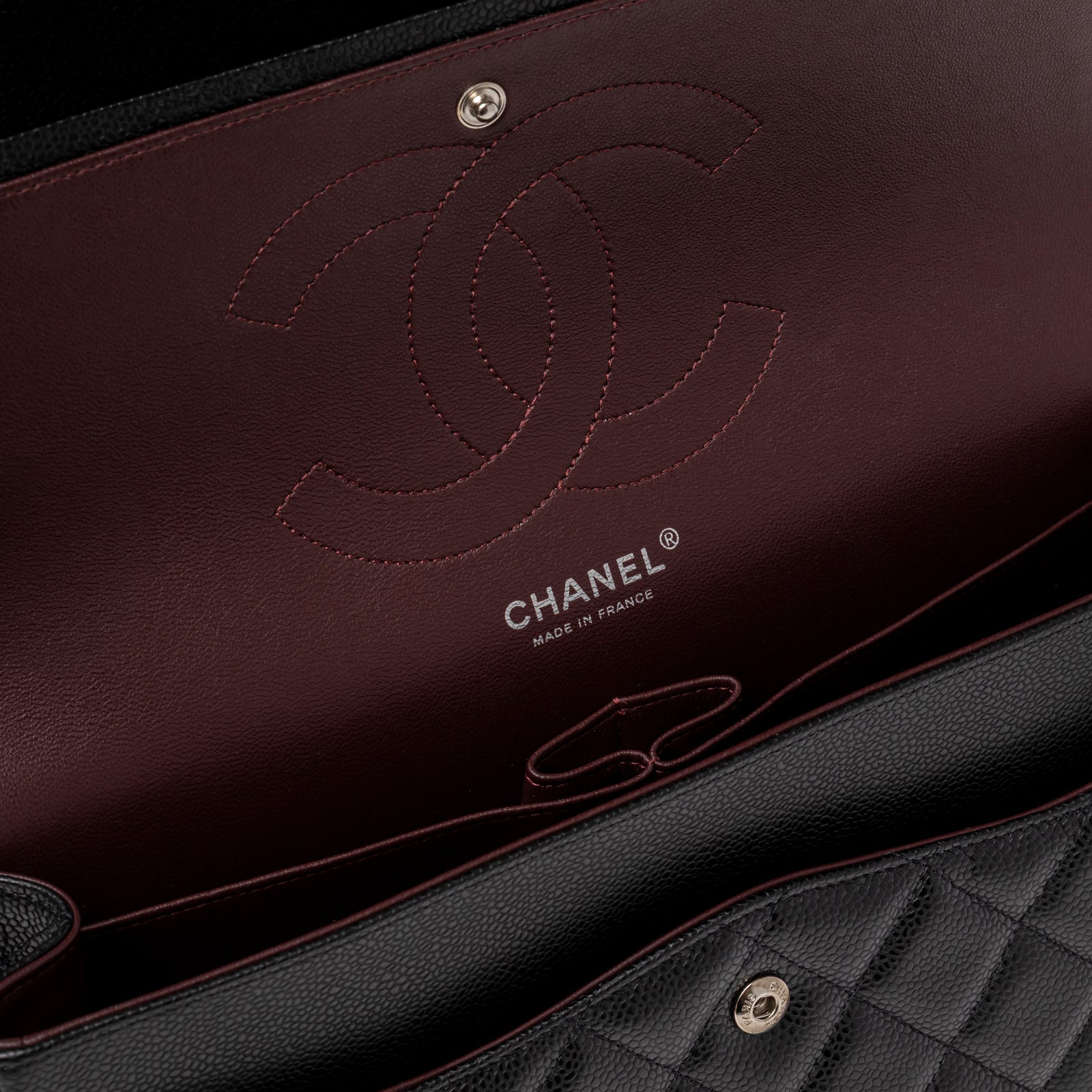 Interior close-up of Chanel Jumbo Classic Double Flap Caviar Black Palladium Hardware showing burgundy lining and embossed logo