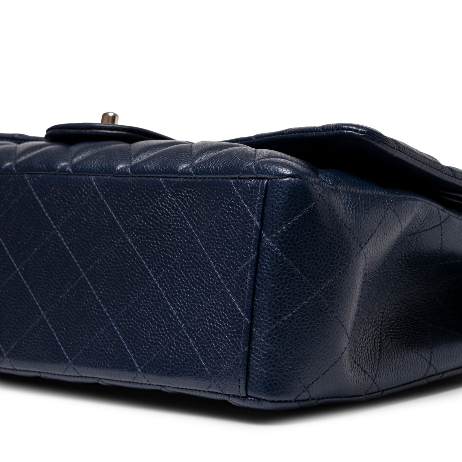 Close-up view of bottom corner on Chanel Maxi Classic Double Flap Caviar Navy Palladium Hardware showing textured leather detail