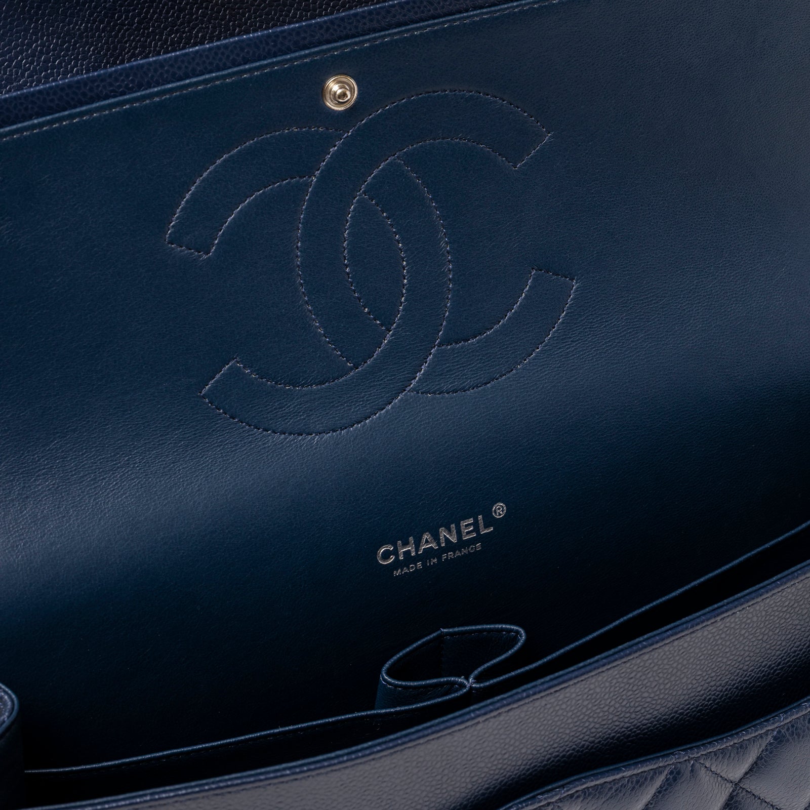 Interior close-up of Chanel Maxi Classic Double Flap Caviar Navy Palladium Hardware showing embossed logo and smooth leather lining